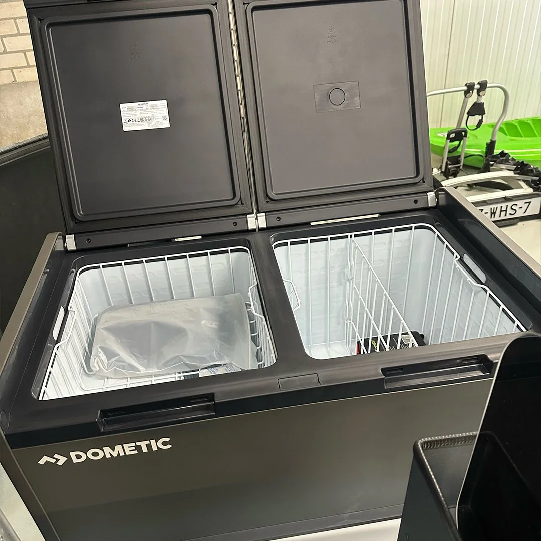 An open Dometic freezer with empty interior and one plastic bag inside.
