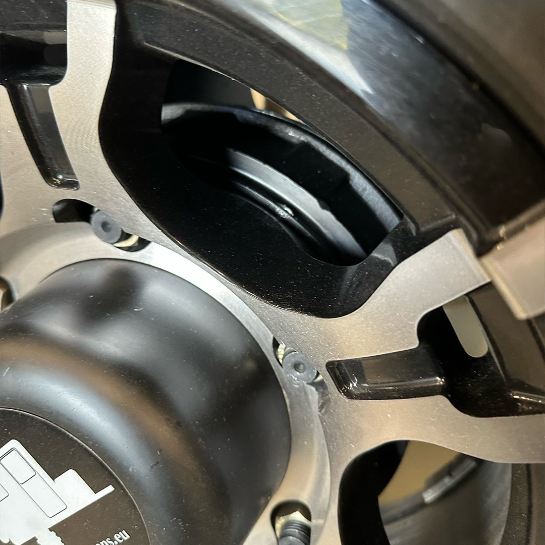 Close-up view of a mechanical or electronic device with metal and black plastic components, bolts, and a central circular part.
