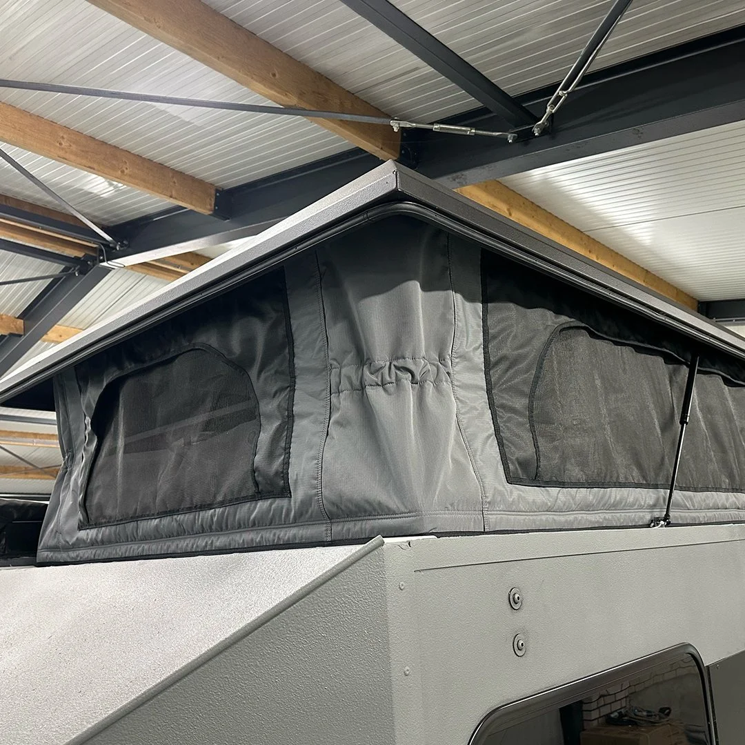 Close-up of a pop-up camper trailer with a raised roof inside a garage.