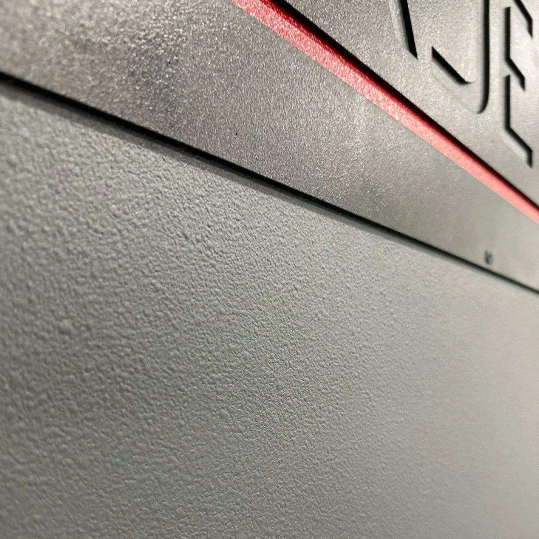 Close-up of a textured, beige computer or electronic device surface with part of a black and red button or panel.