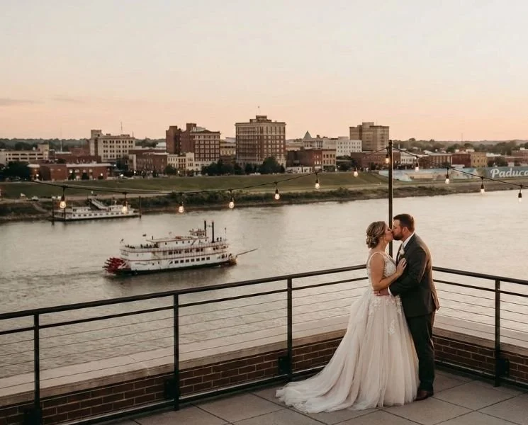 Bride and groom embraced downtown overlooking the ohio river with a boat in the background
