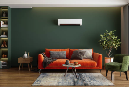 Modern living room with orange sofa, green wall, air conditioner, and potted plant. Roofing and painting in Bucks County