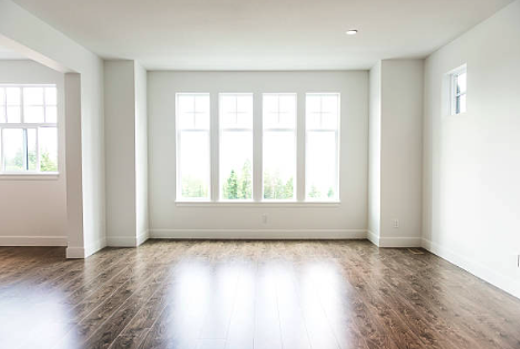 Bright empty living room with hardwood floors and large windows. Roofing and painting in Bucks County
