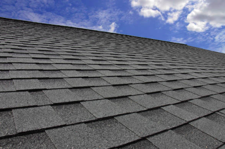 Asphalt shingle roof under a blue sky with clouds