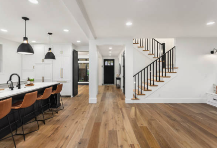 Modern kitchen and staircase in open-concept home with wooden floors, white walls, black accents, and a kitchen island with brown chairs. Roofing and painting in Bucks County
