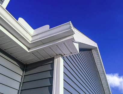 Close-up of house with vinyl siding and soffit against blue sky
