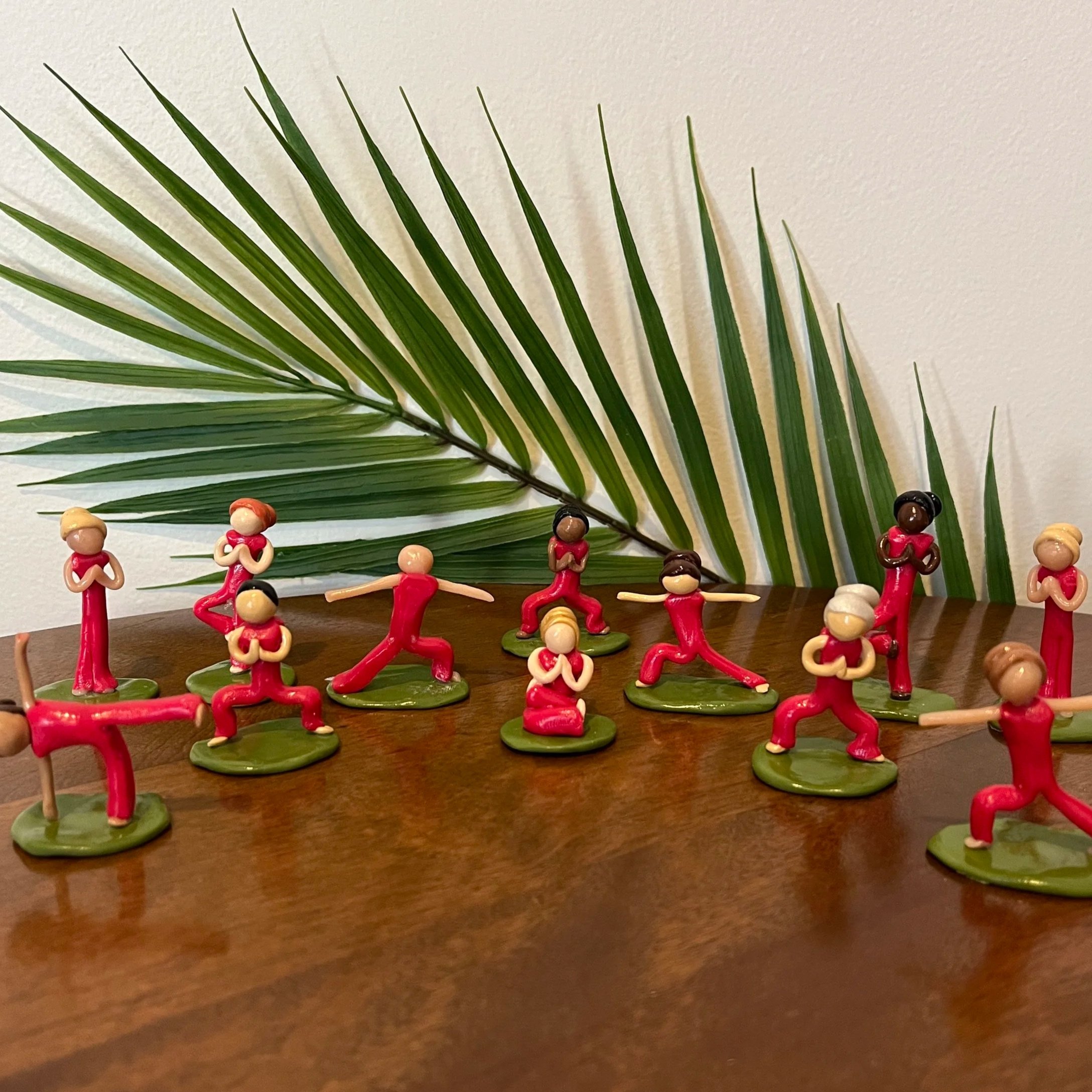 Twelve clay yogi sculptures by Alexis Velez Pearlman practicing in various poses.