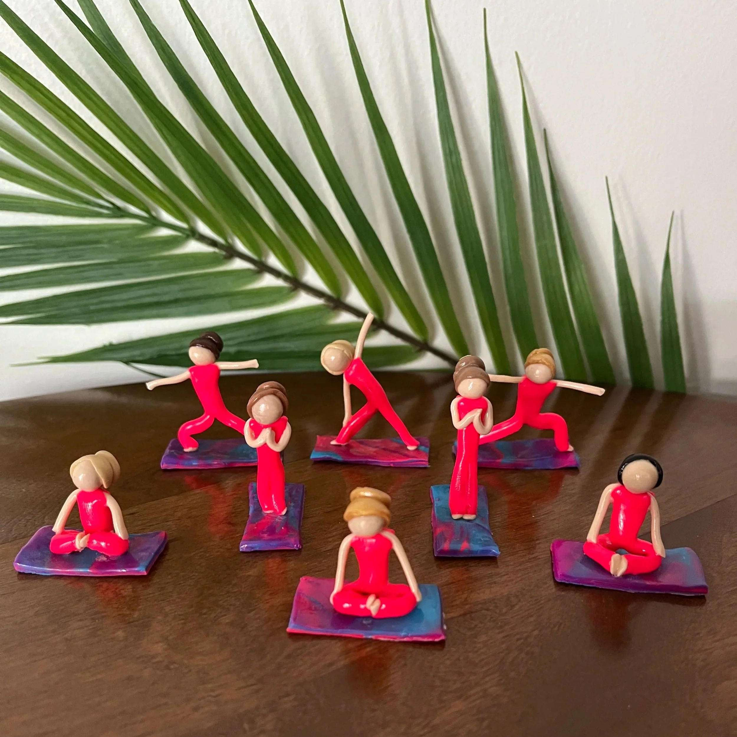 Eight clay yogi sculptures by Alexis Velez Pearlman practicing in various poses.