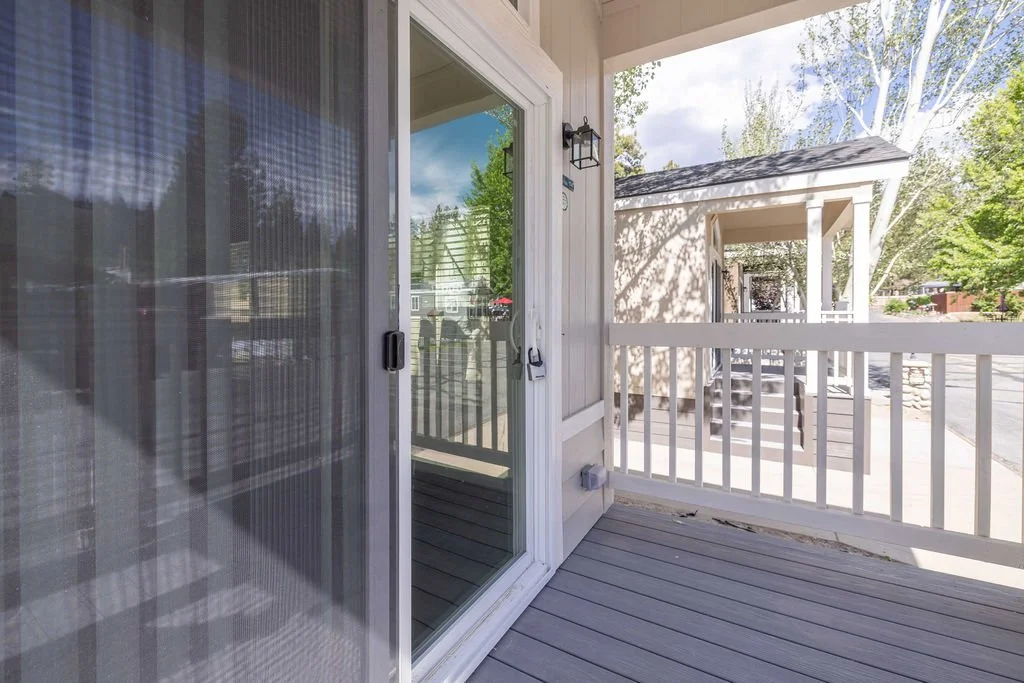 Front porch of a tiny home at Big Bear Mobile Estates with outdoor seating overlooking the community.