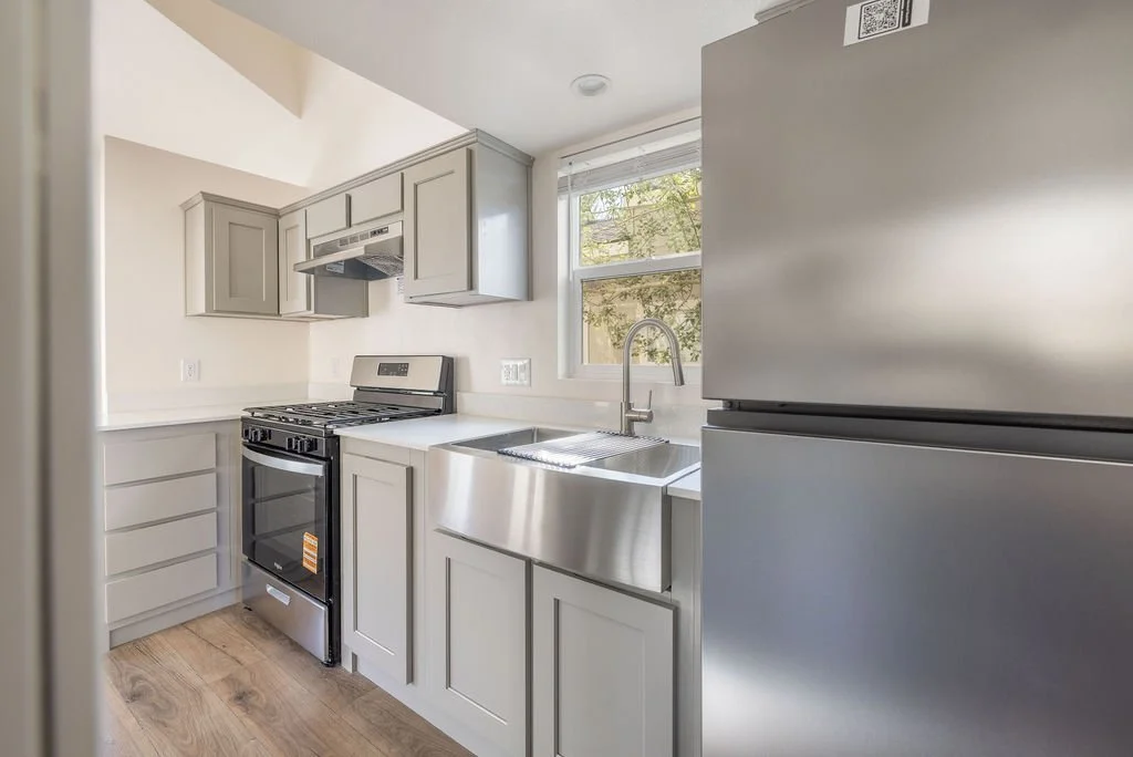 Modern kitchen interior of a new tiny home for sale at Big Bear Mobile Estates with gray cabinets and stainless steel appliances.