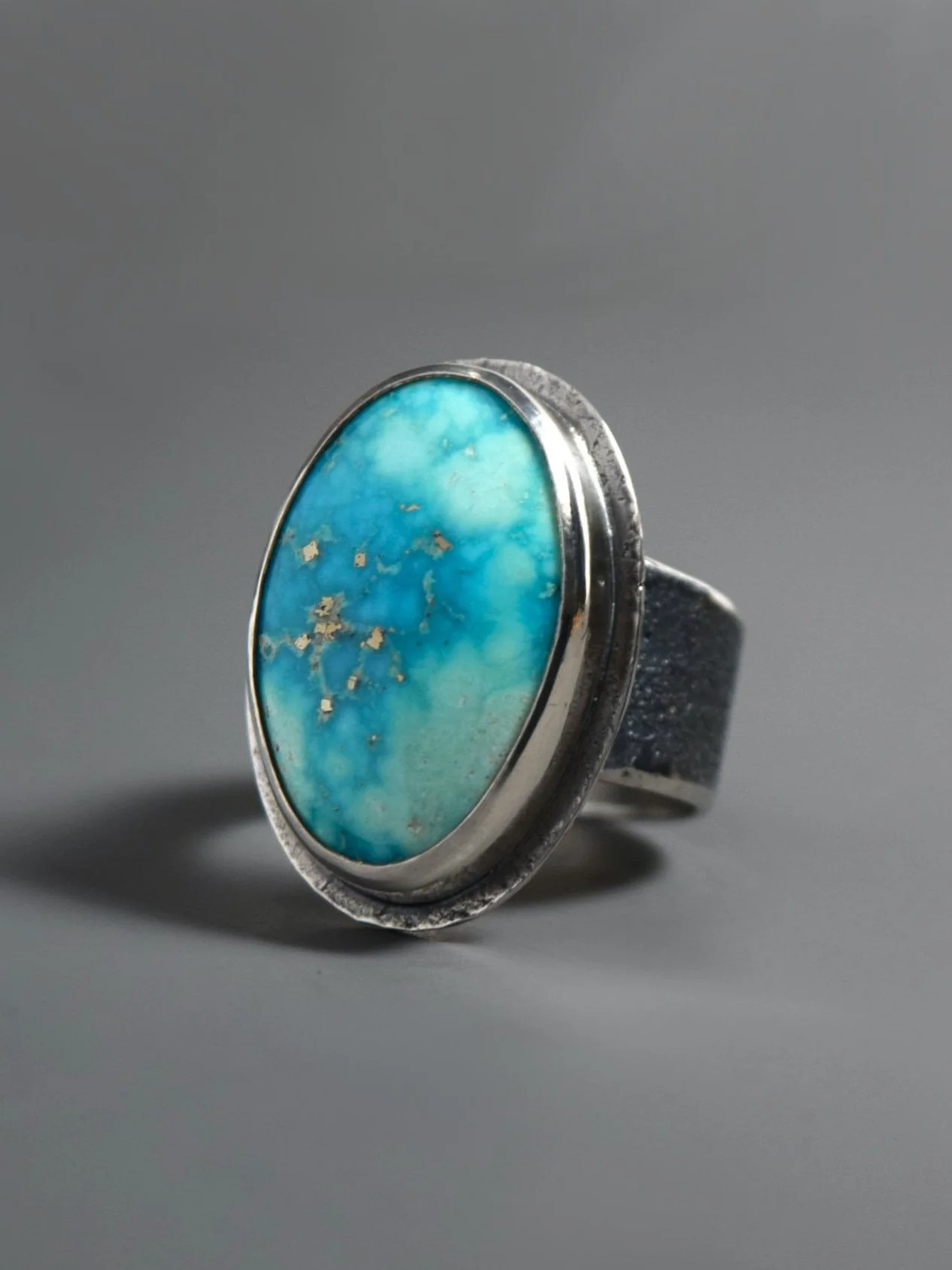 Silver ring with an oval turquoise stone on a gray background.