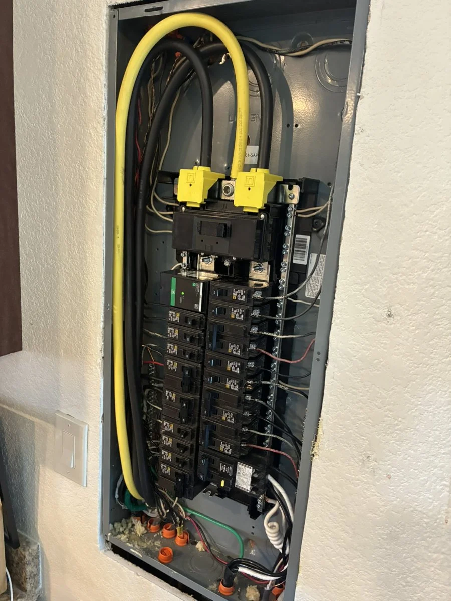 an electric panel opened with breakers and various wires visible.