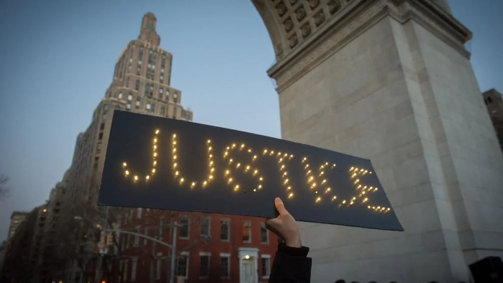 Hand holding up sign saying Justice
