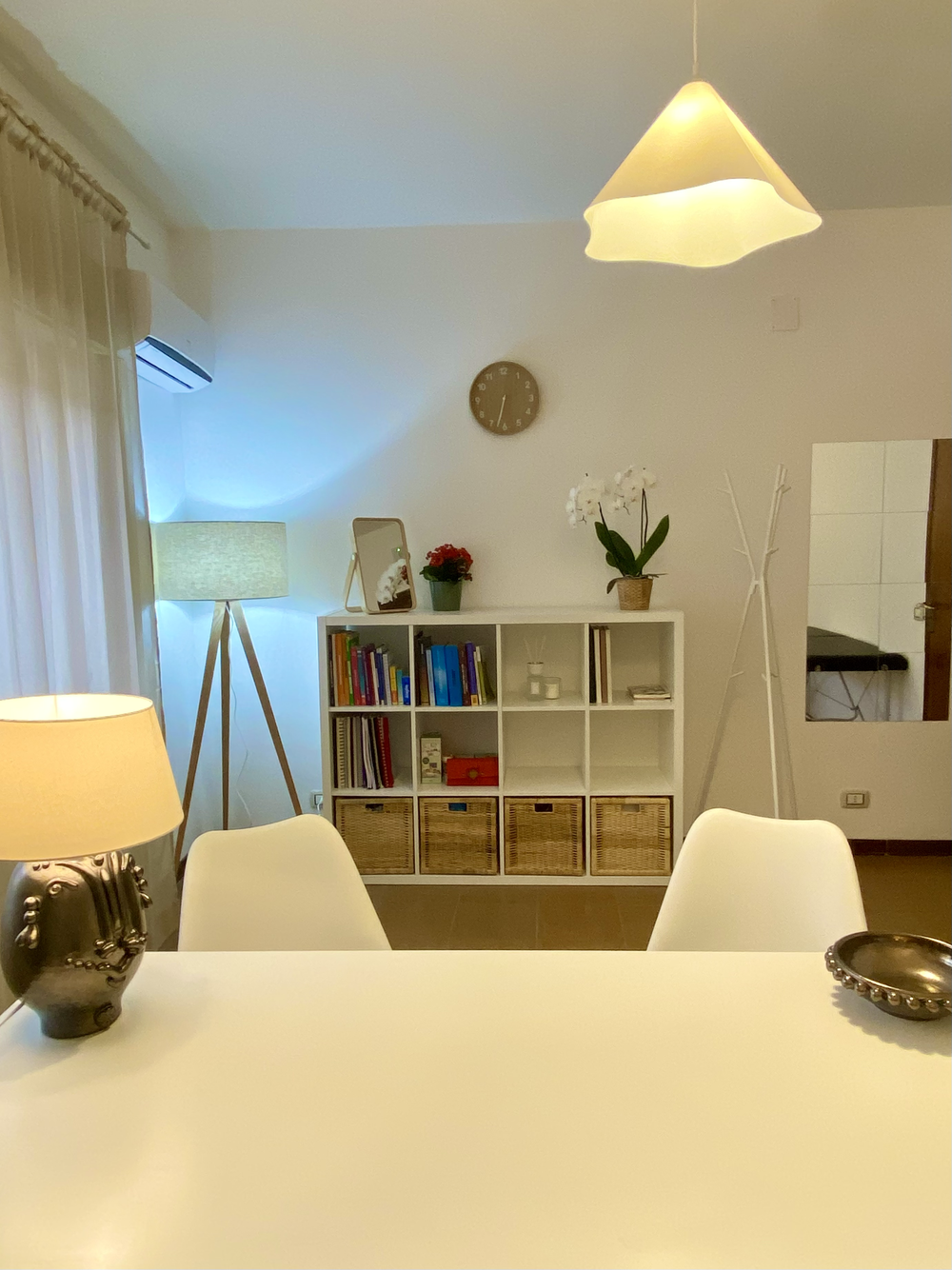 Sala dello studio con tavolo bianco, lampada e libreria con giochi