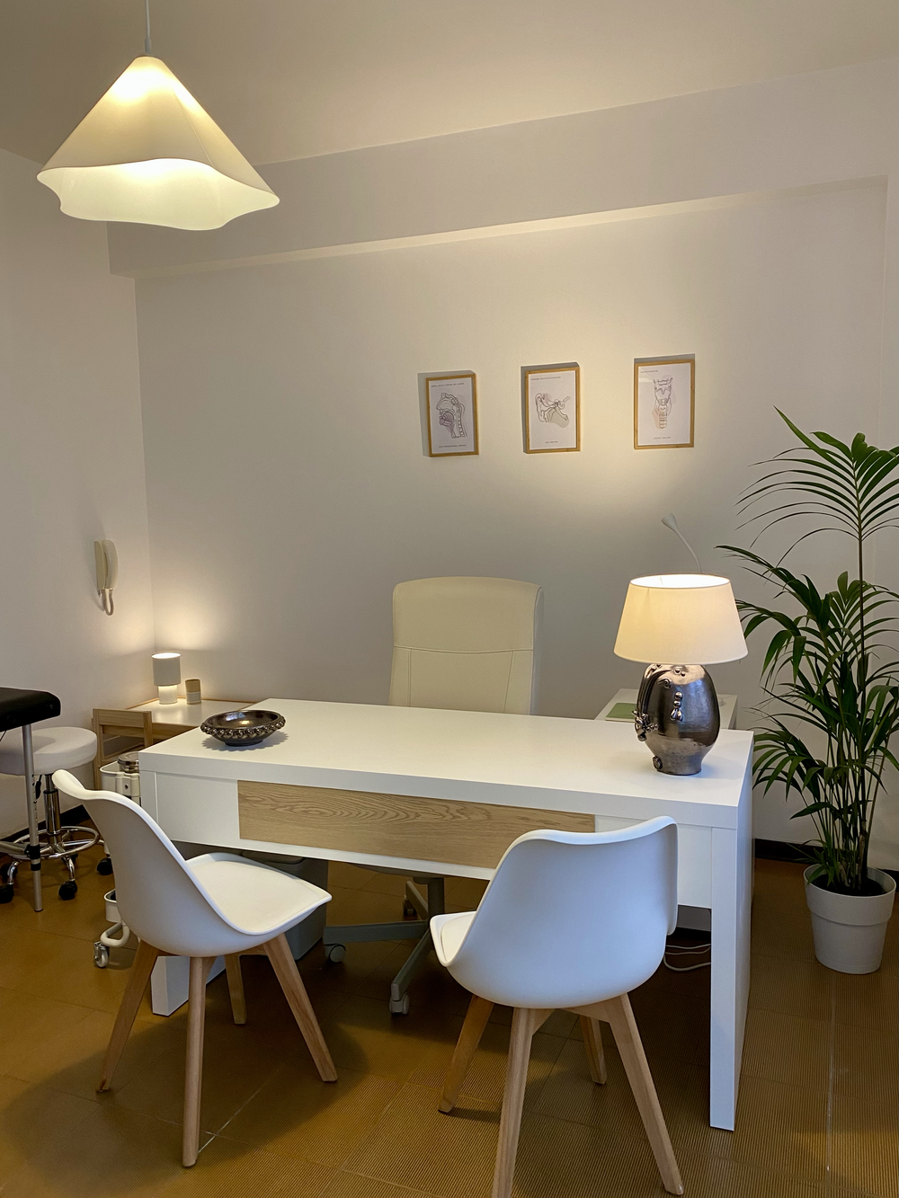 Sala di terapia luminosa con scrivania bianca, lampada e pianta