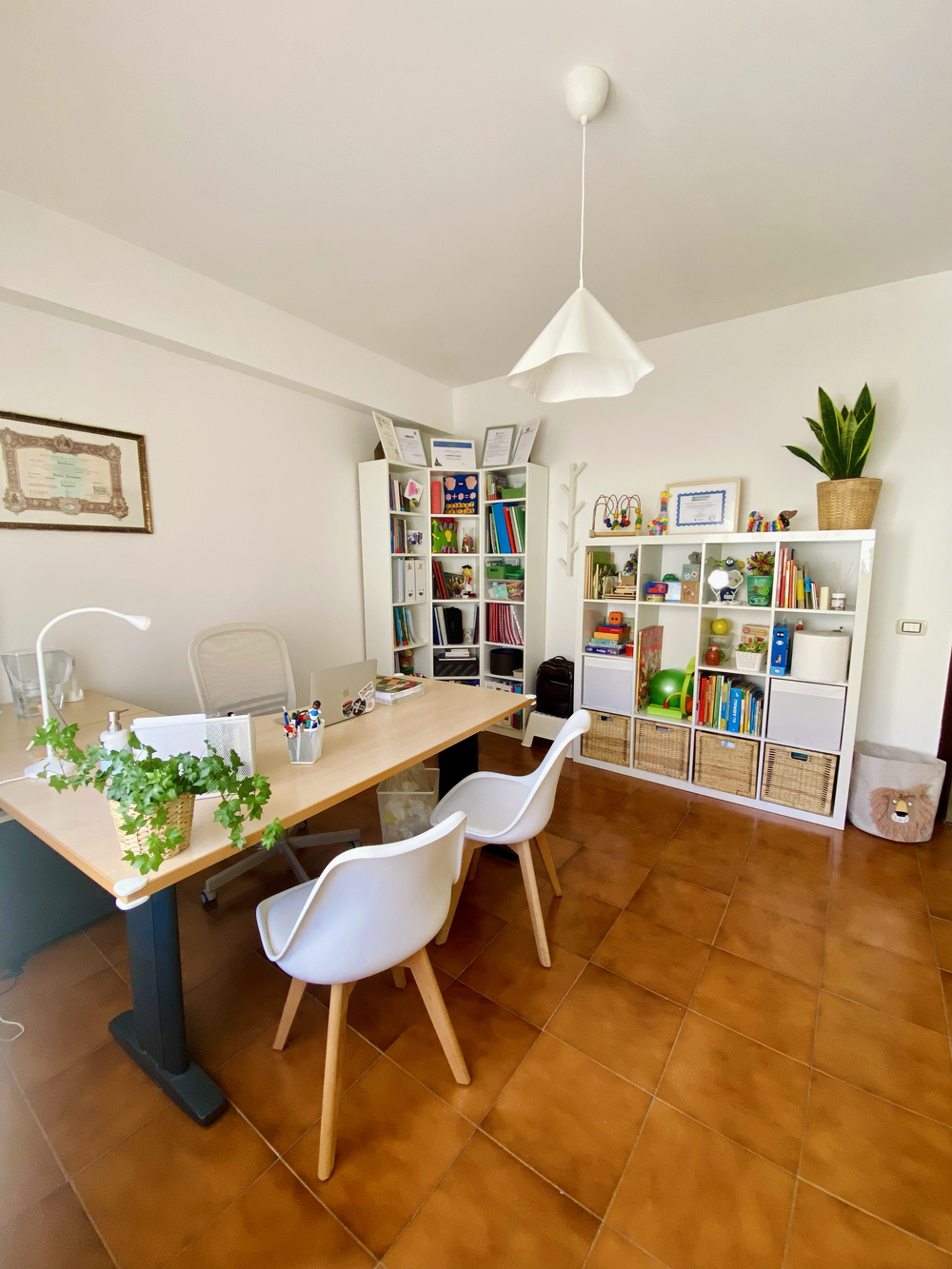 Sala di terapia dello studio riabiliTIAMO con scrivania e libreria con giochi