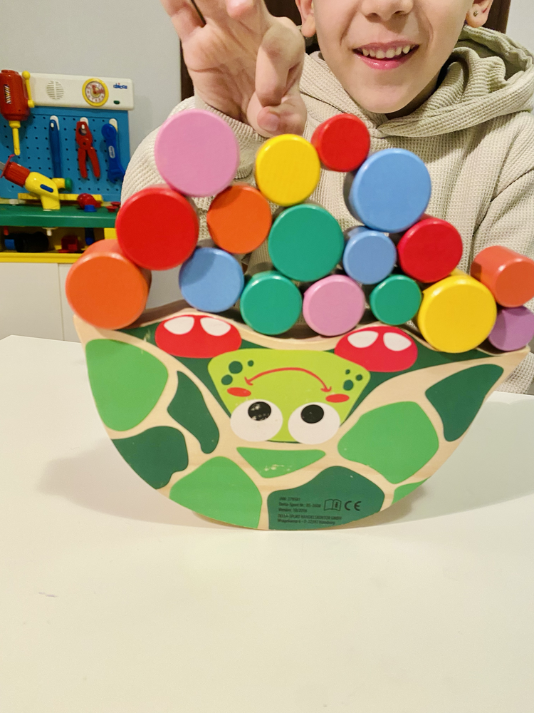 Bambino sorridente con un gioco di legno colorato
