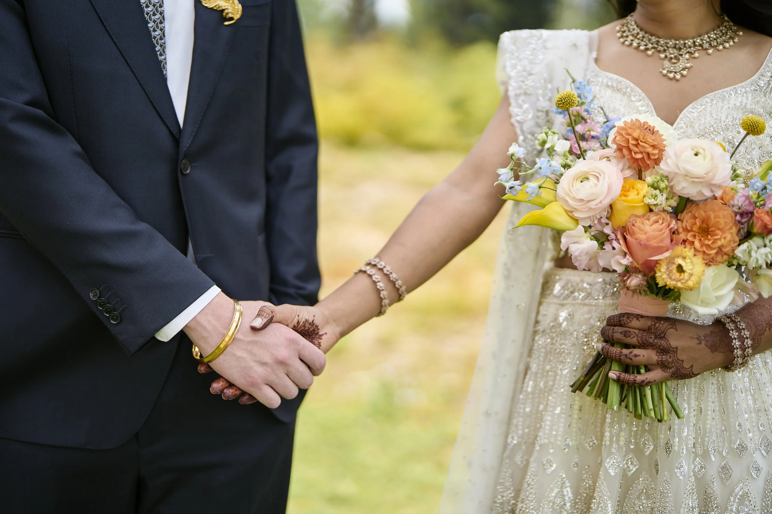 A bride (with henna on her hands and wrists) and groom holding hands