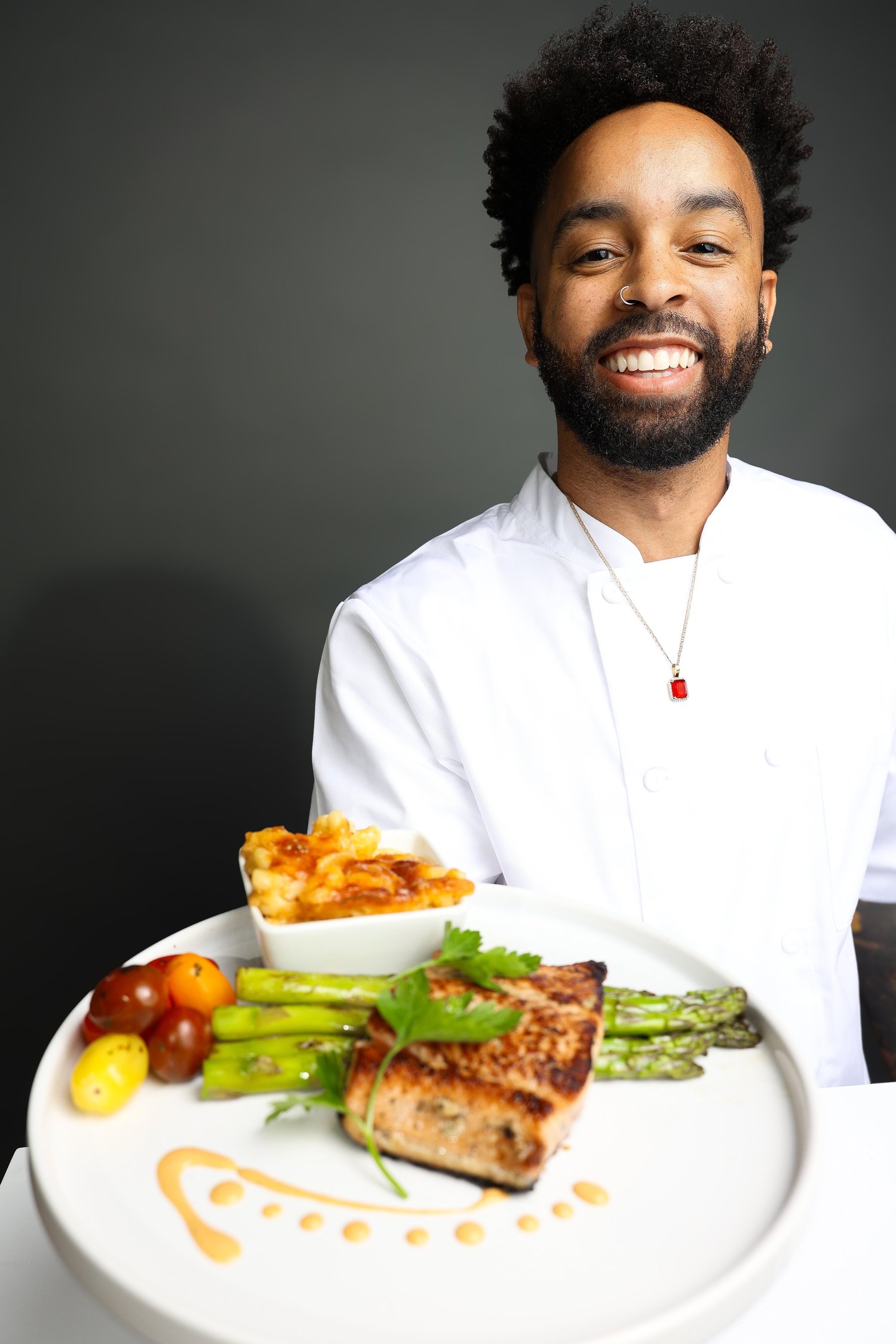 Chef Ahmir in chef's whites, holding a plated dish