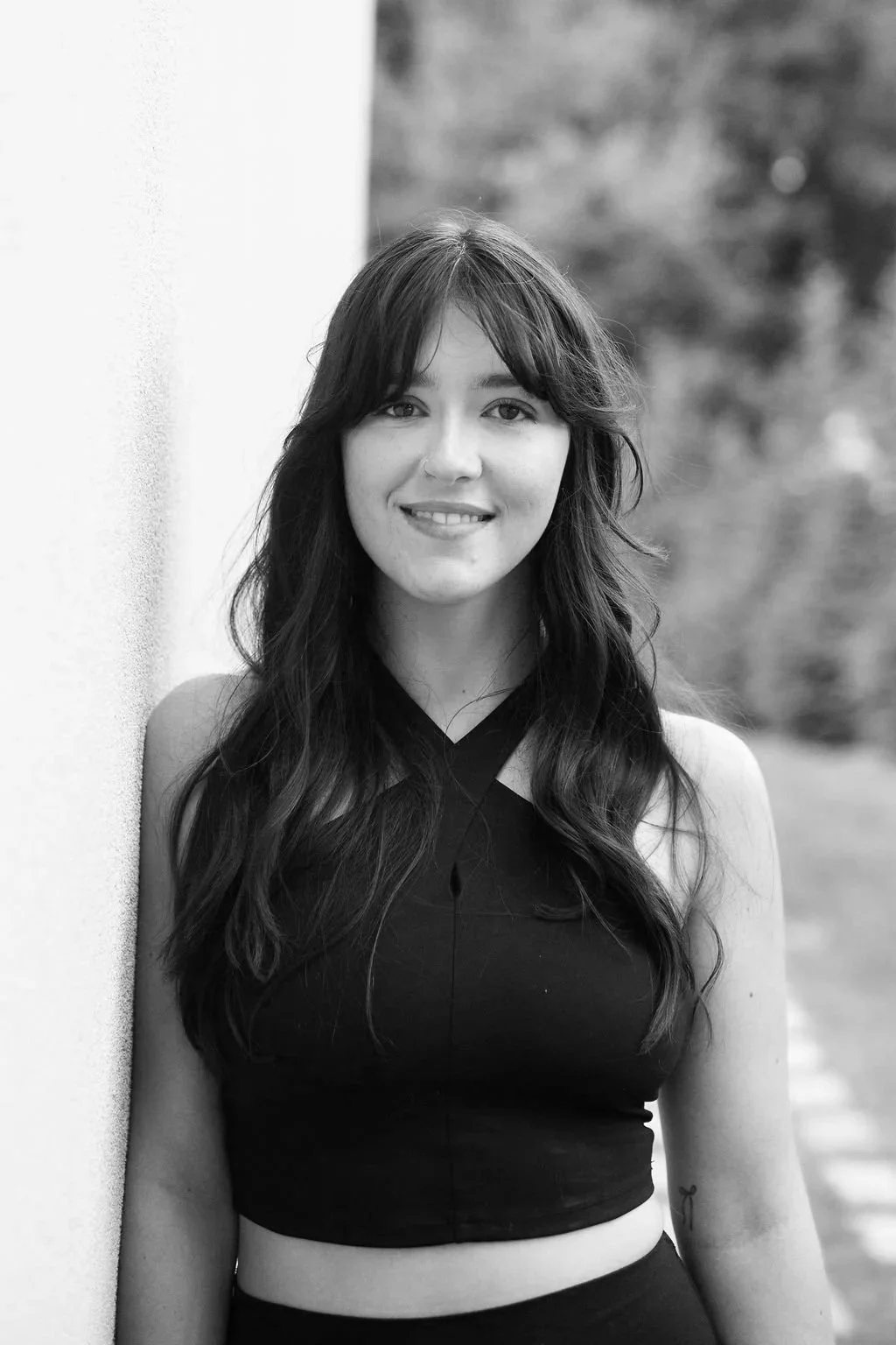 A woman practicing yoga in front of a mirror in a dimly lit room with candles and bottles on a table, performing a side stretch pose.