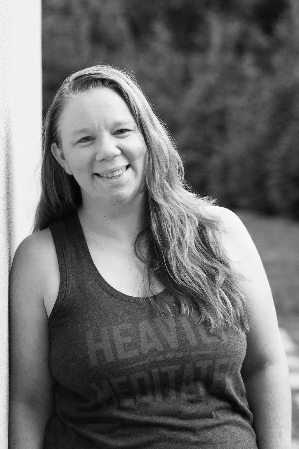 A woman with long, wavy hair smiling at the camera in a black-and-white photo.