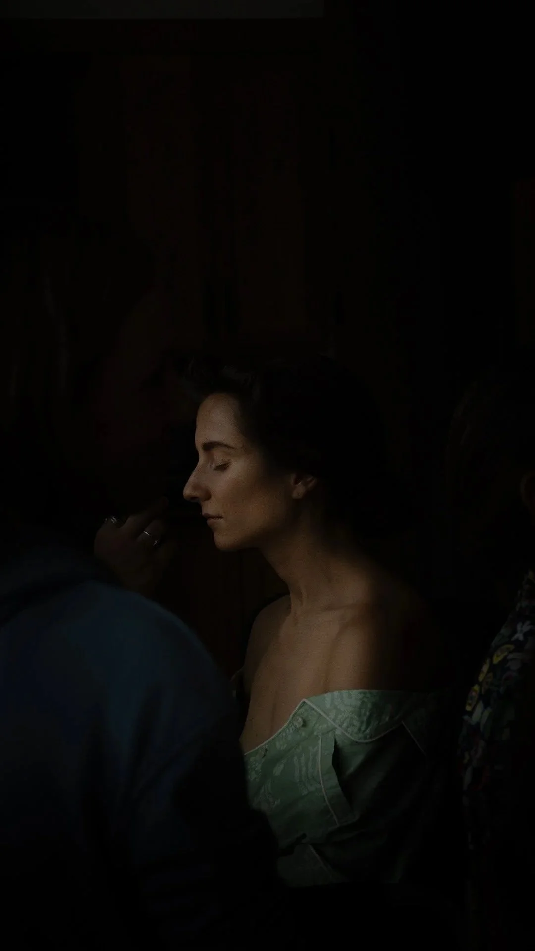 A woman with closed eyes and a serene expression, surrounded by people in a dark room.