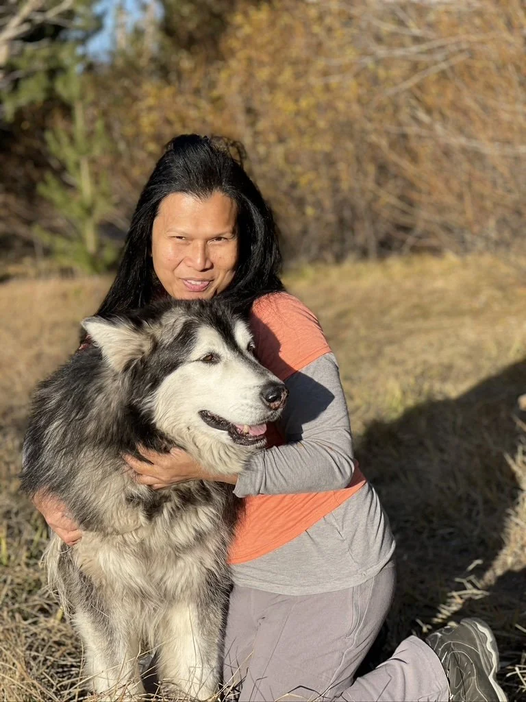 Woman holding a black-and-white Malamute outdoors.