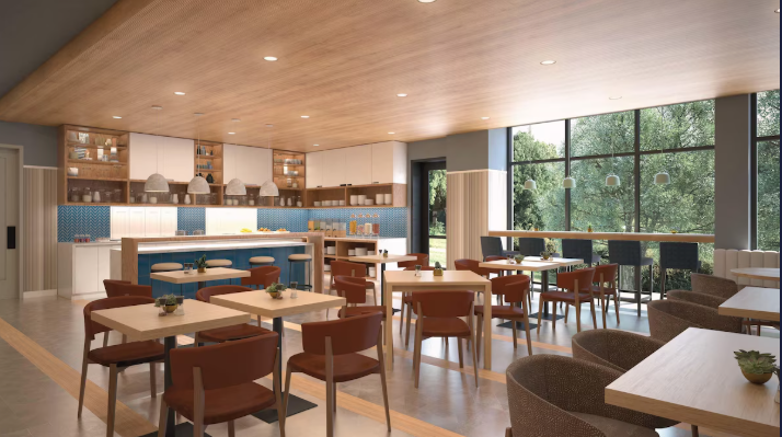 Modern dining area with wooden ceiling, large glass windows, multiple tables and chairs, and a kitchen with white cabinets and blue backsplash
