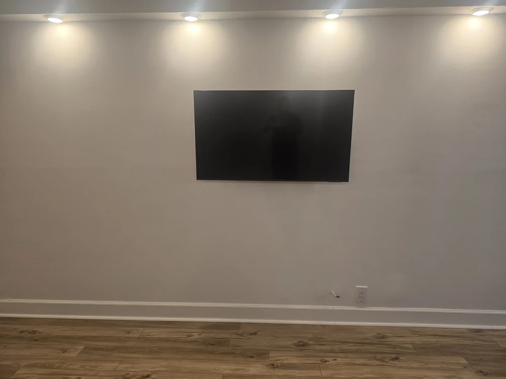 Gallery-style TV wall mounting with zero visible cables under custom spotlighting