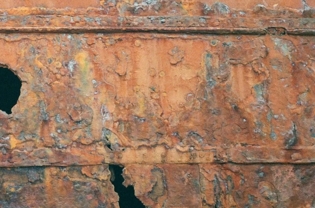 Close-up of a rusted metal surface with multiple holes and peeling corrosion.
