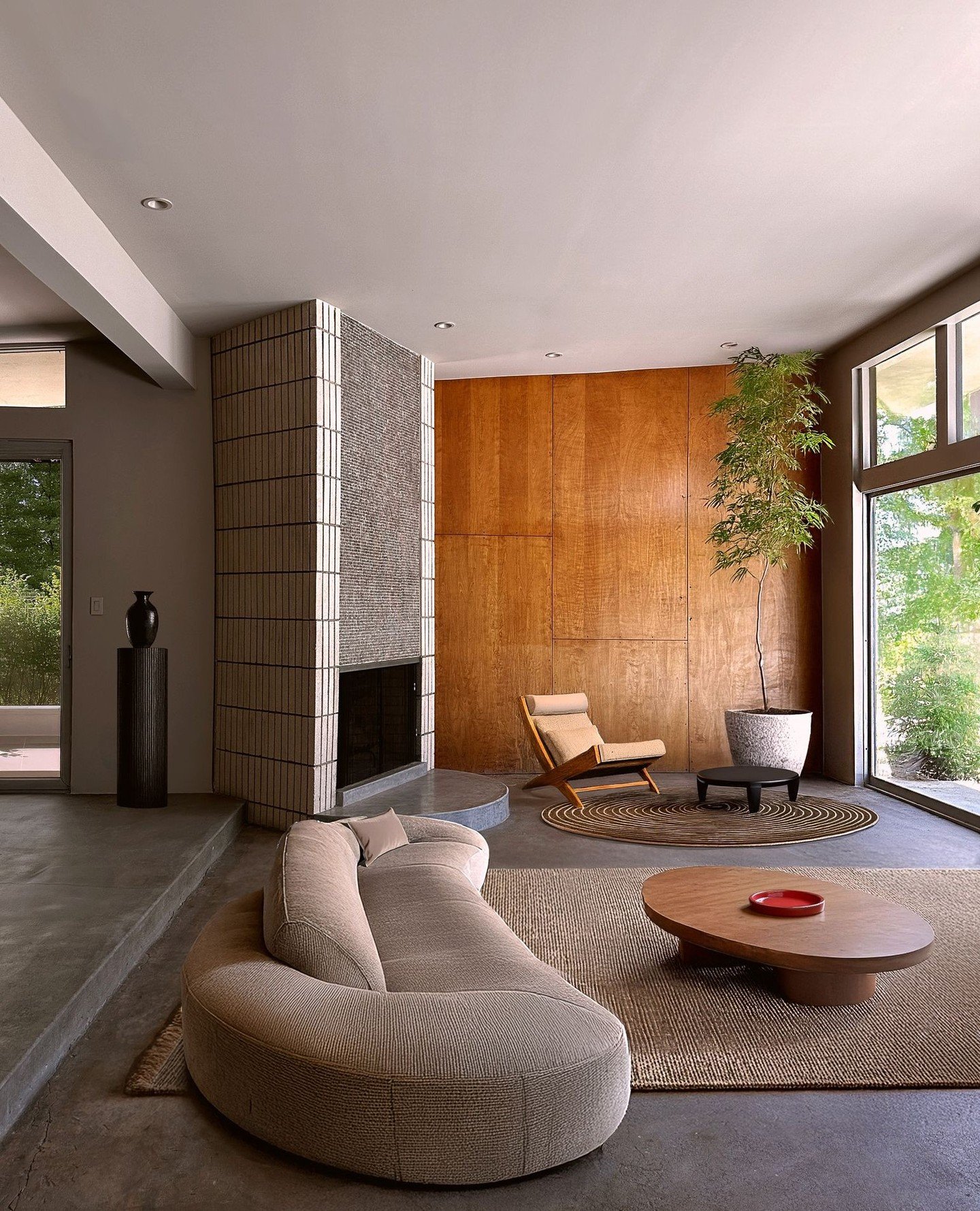 In our mid-century modern project in Carmel-by-the-Sea, every detail tells a story. A custom curved sofa, inspired by vintage design, takes center stage, while a natural sisal rug grounds the living room. The original brick fireplace and maple-panele