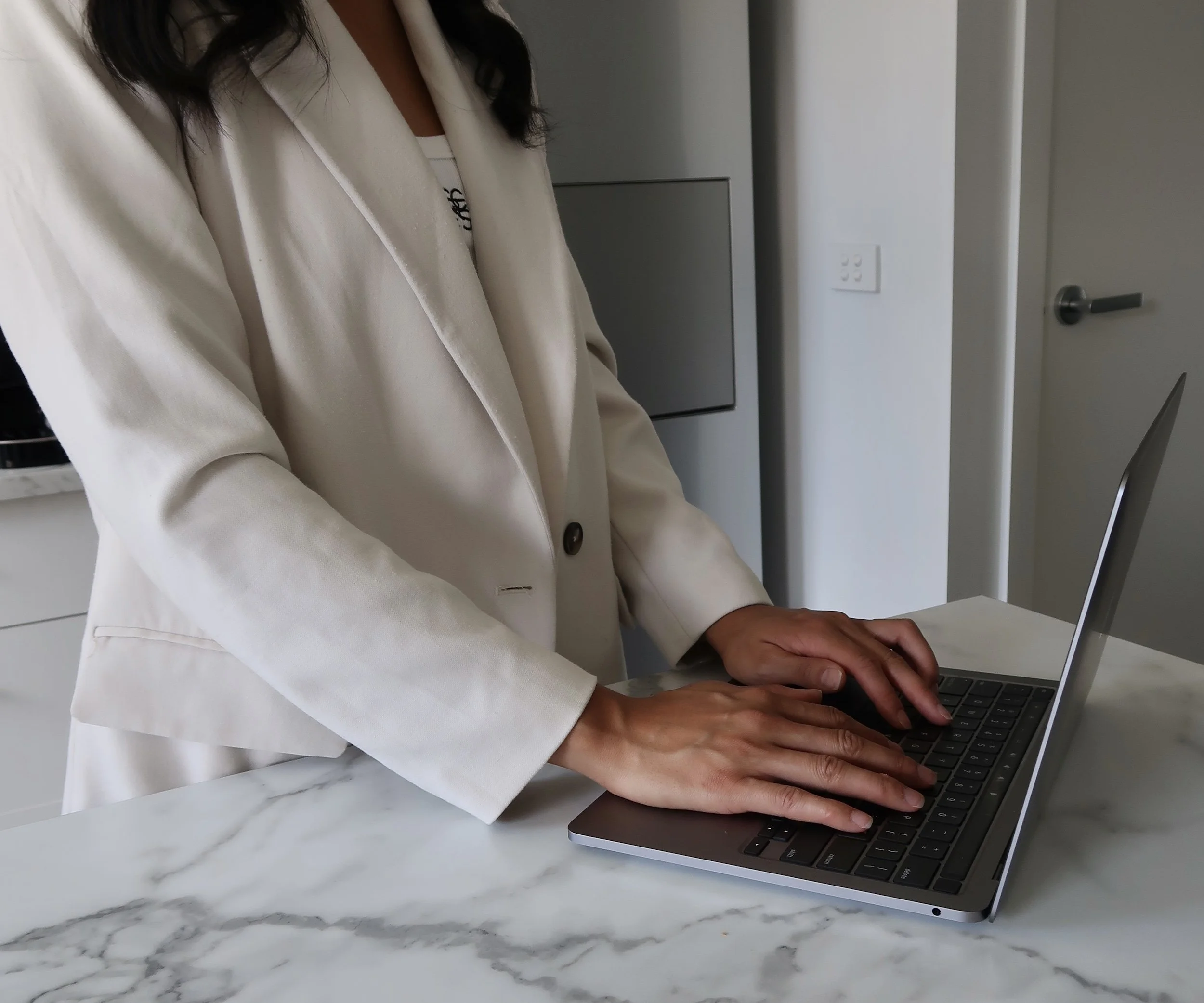 Woman in beige blazer typing on laptop