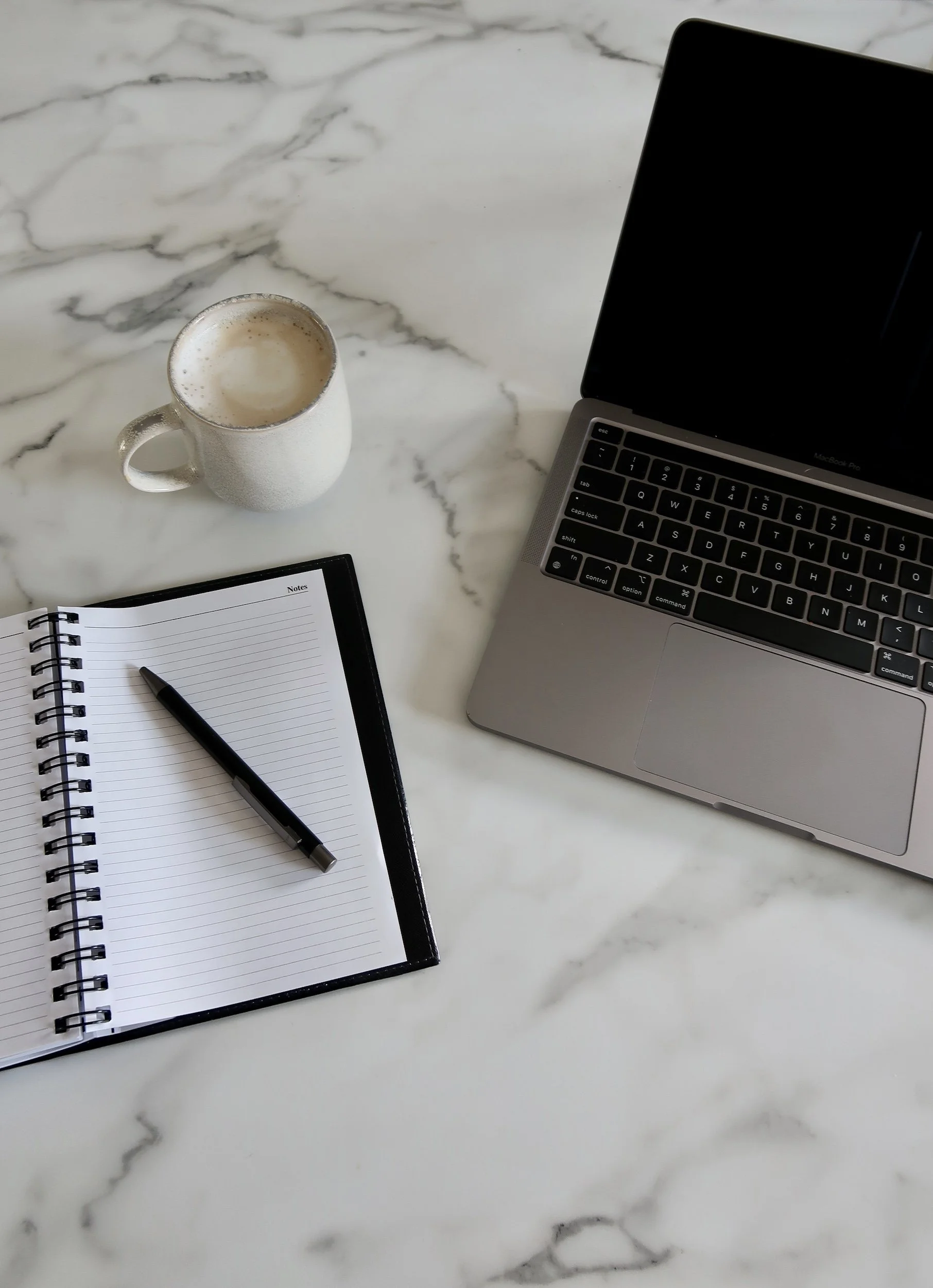 Coffee, notebook and laptop on marble table