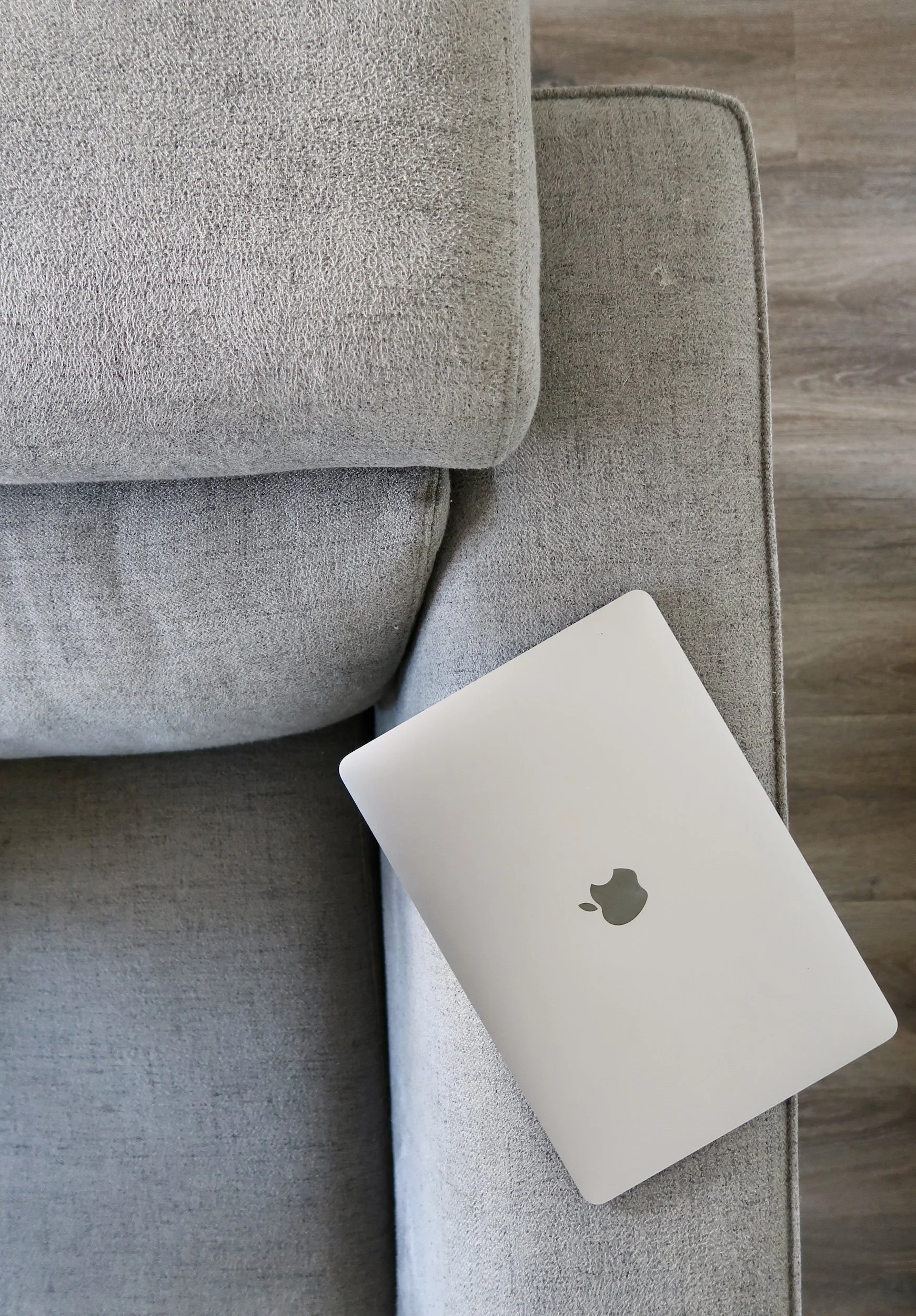 Laptop resting on grey couch
