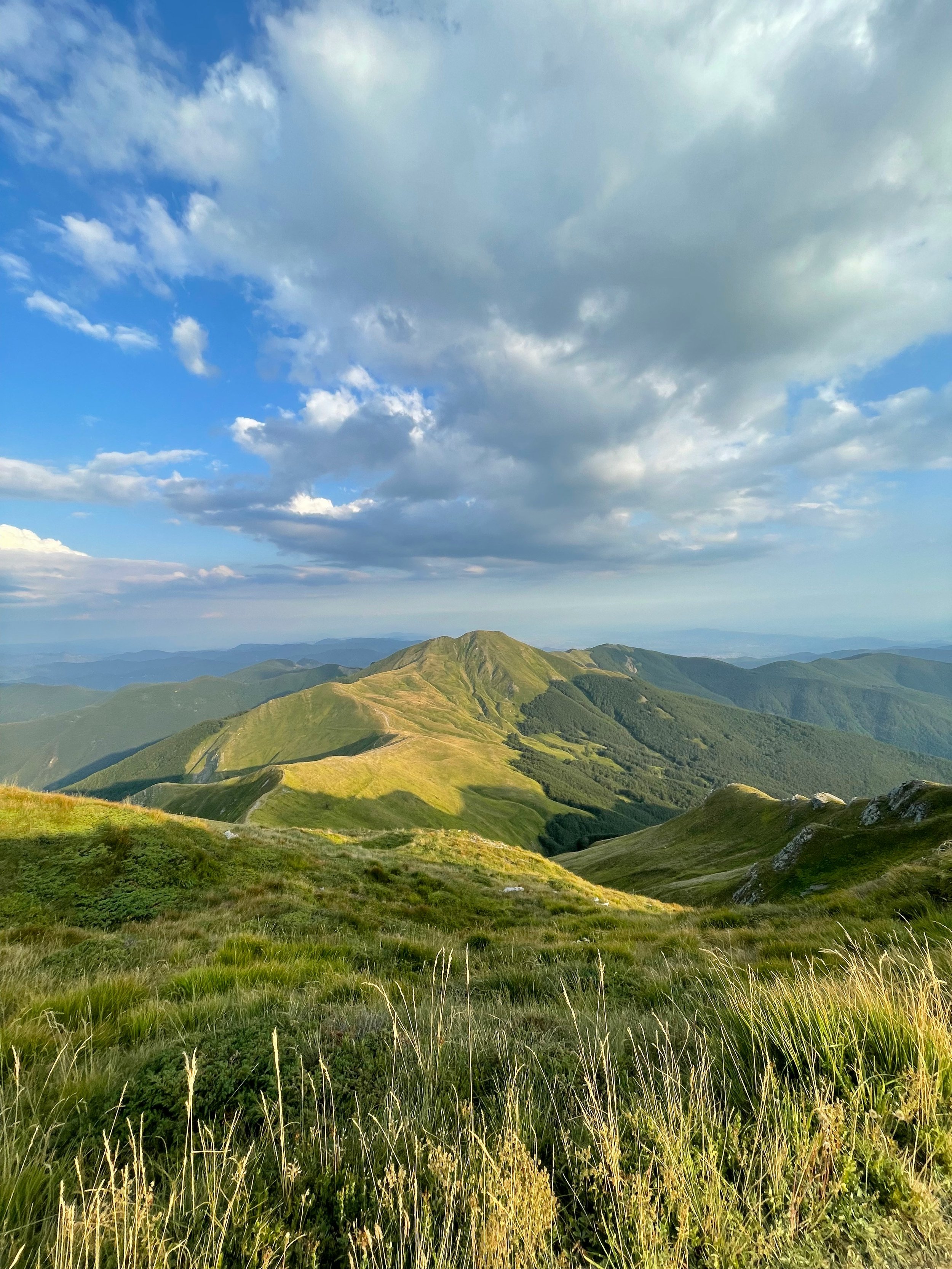Scenic view of lush green mountains under a partly cloudy sky.