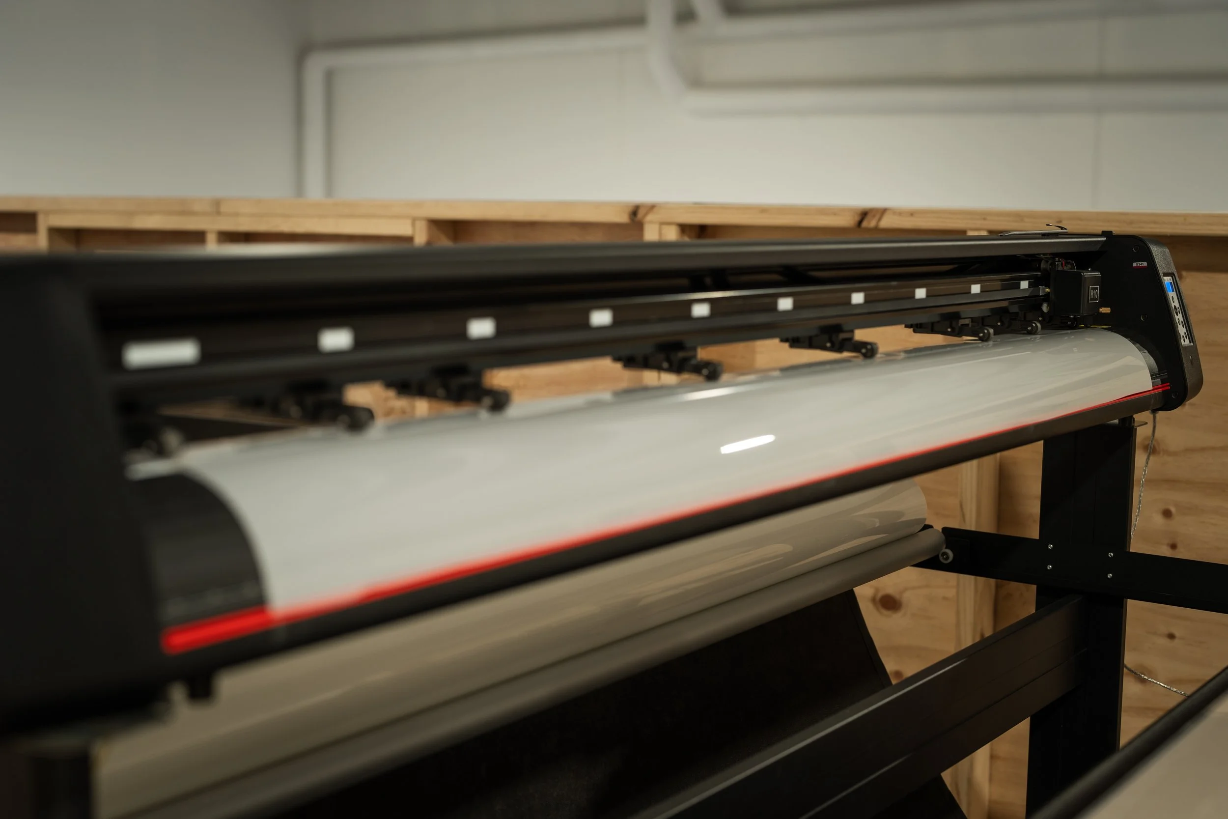 Large format printer in a workshop with wooden walls.