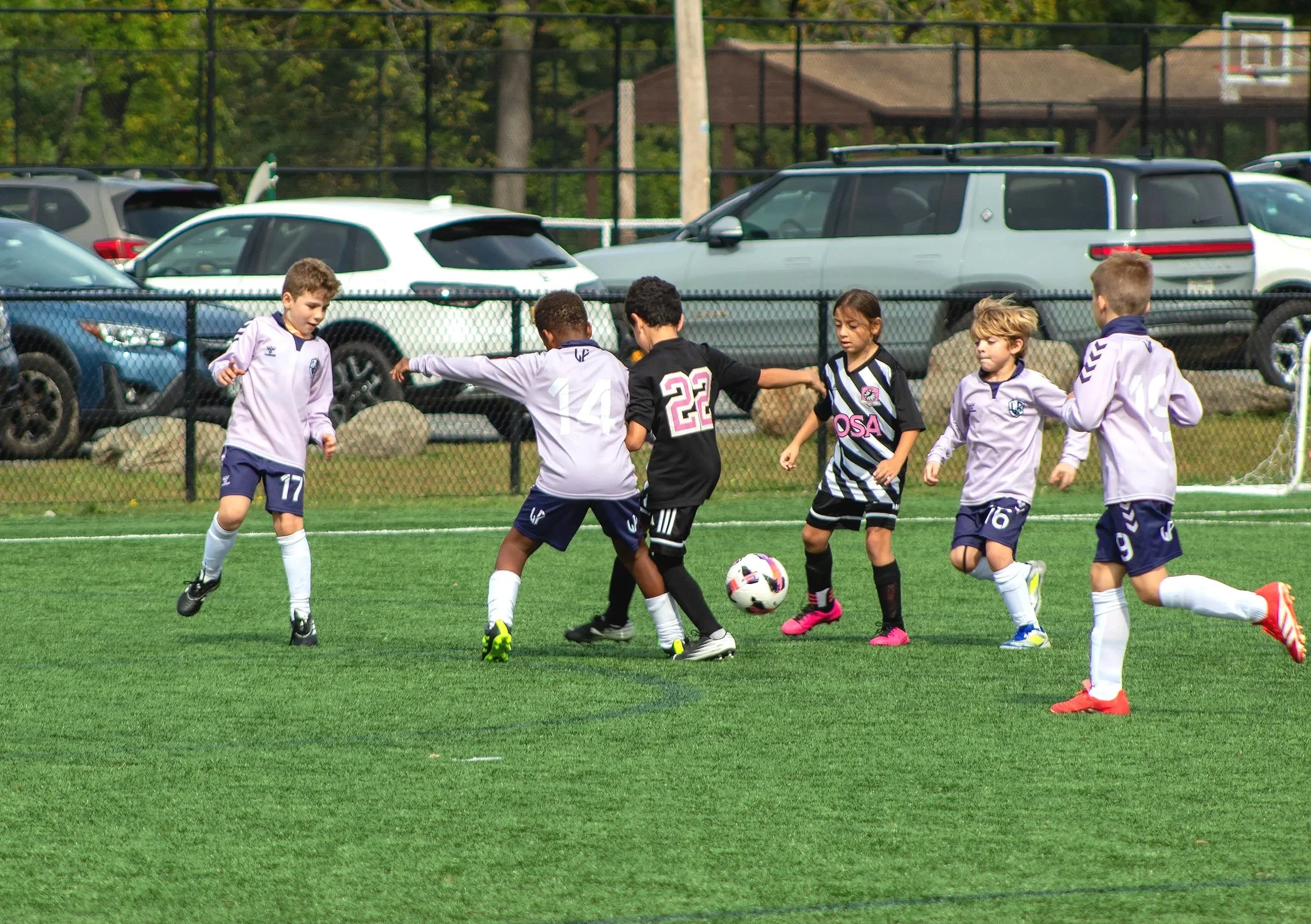 Kids playing soccer on a green field during daytime.
