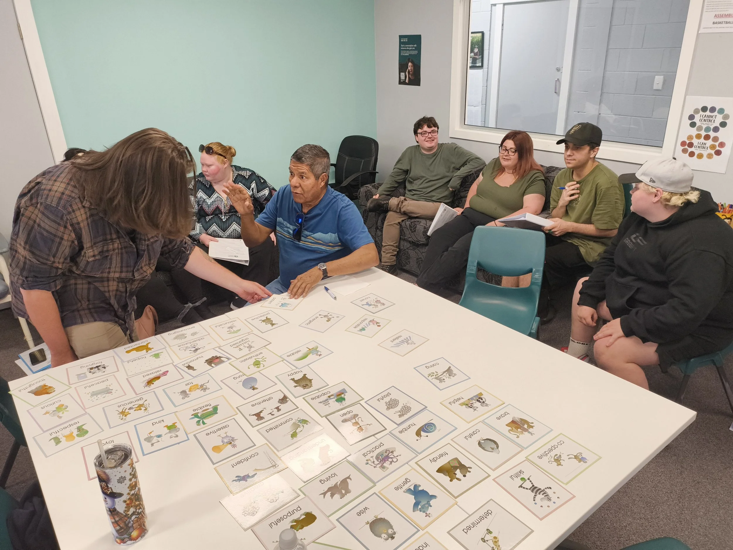 Group of eight women standing outdoors on a sunny day, with a brick building, trees, and a sidewalk in the background.