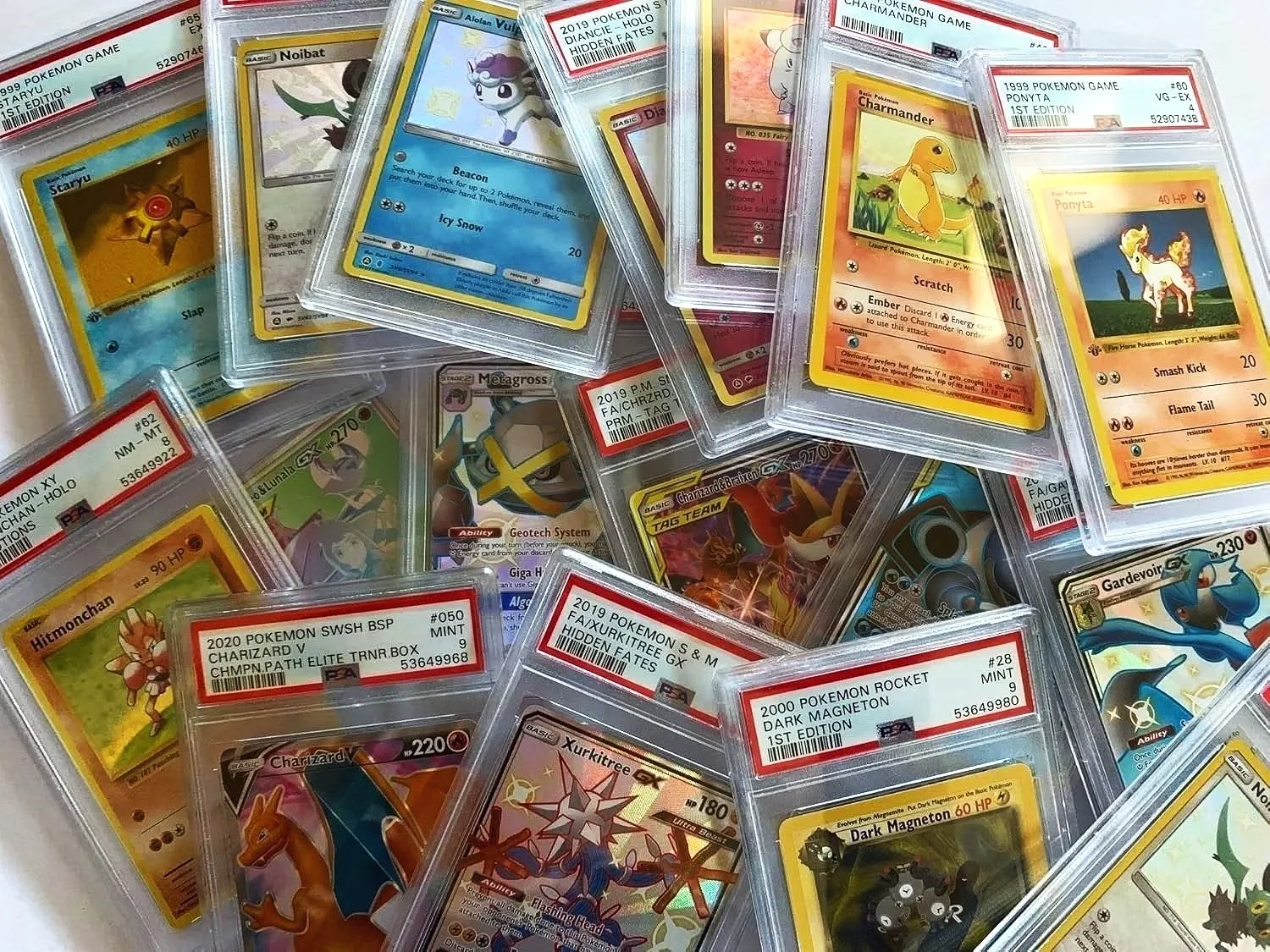 A collection of graded Pokémon trading cards in clear protective cases, including Pikachu, Charmander, Gardevoir, and Charizard.