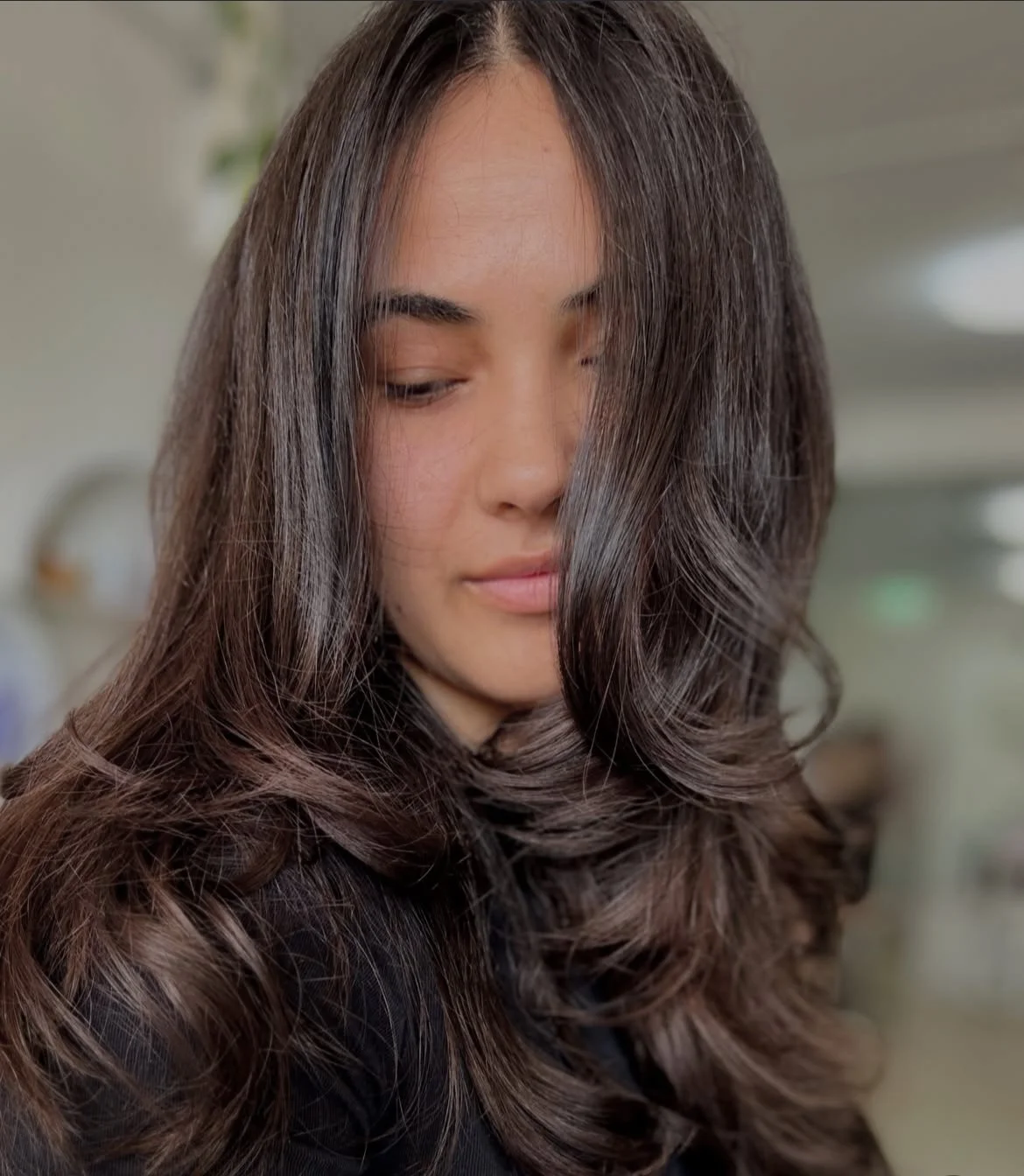 Woman with long, wavy brunette hair with lots of bouncy layers.