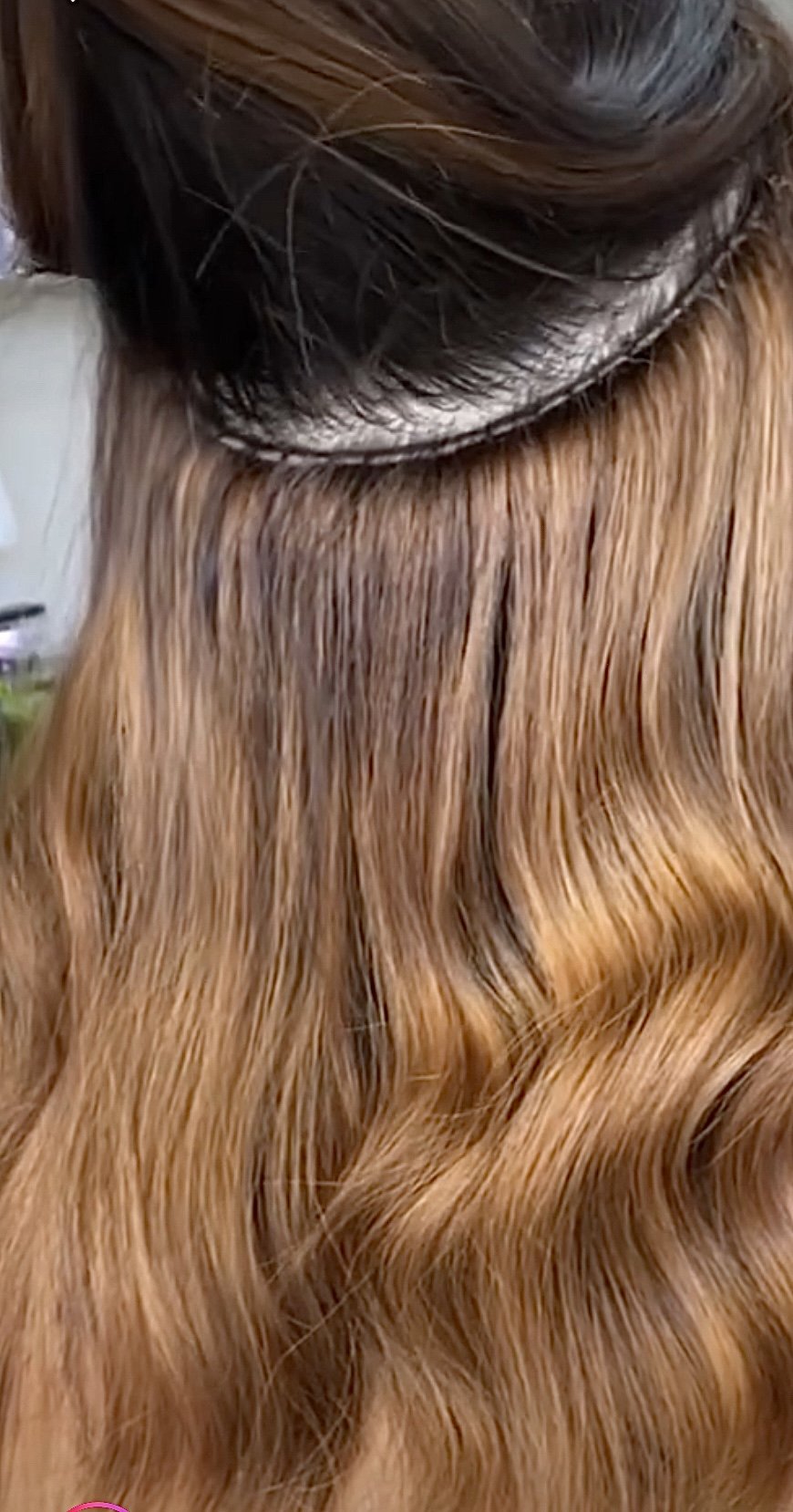 Hairstylist attaching hair extensions to a woman's head.