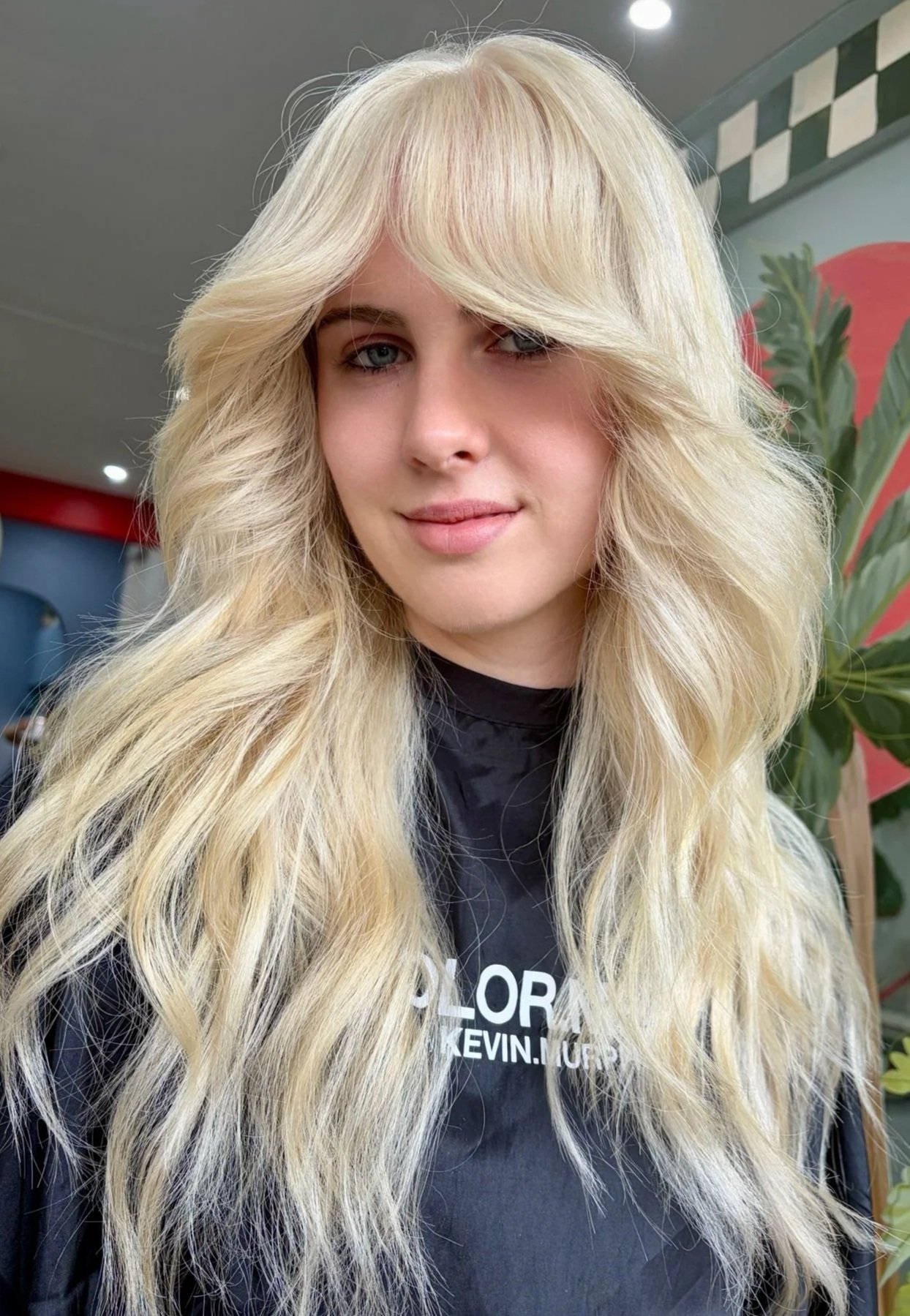 Woman with long, wavy, blonde hair and butterfly tattoo on shoulder.