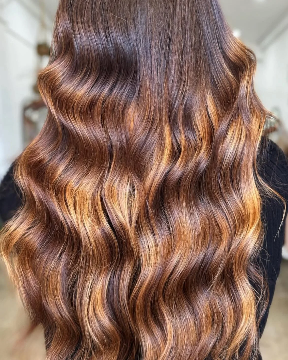 Wavy long extensions in hair with a copper and brunette colour