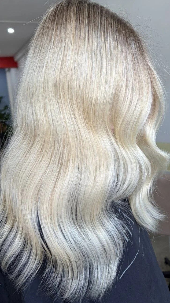 Woman with long, wavy blonde hair and butterfly tattoo on shoulder