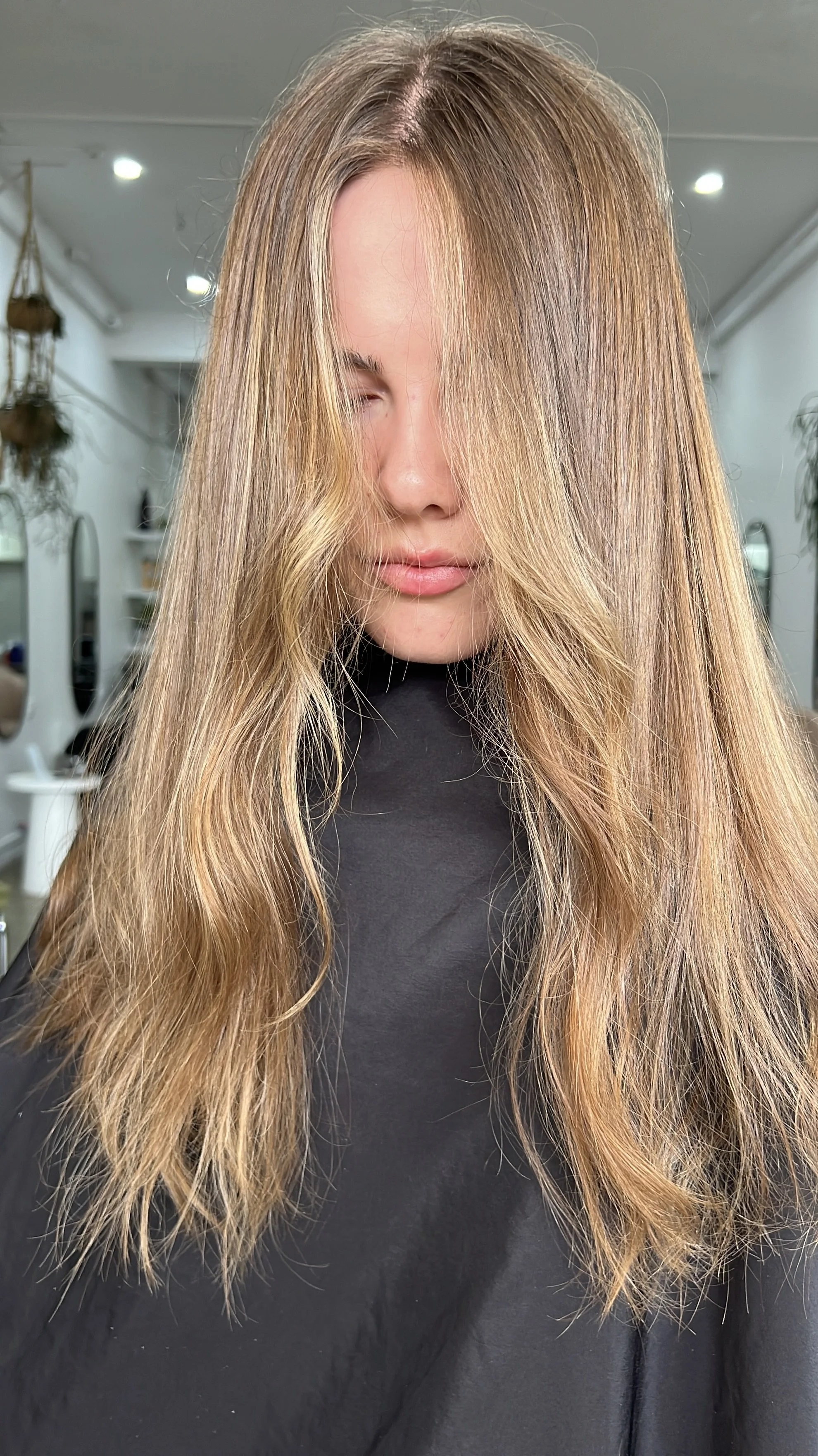 Close-up of a person with long, straight naturally coloured hair, slightly highlighted, wearing a black top.