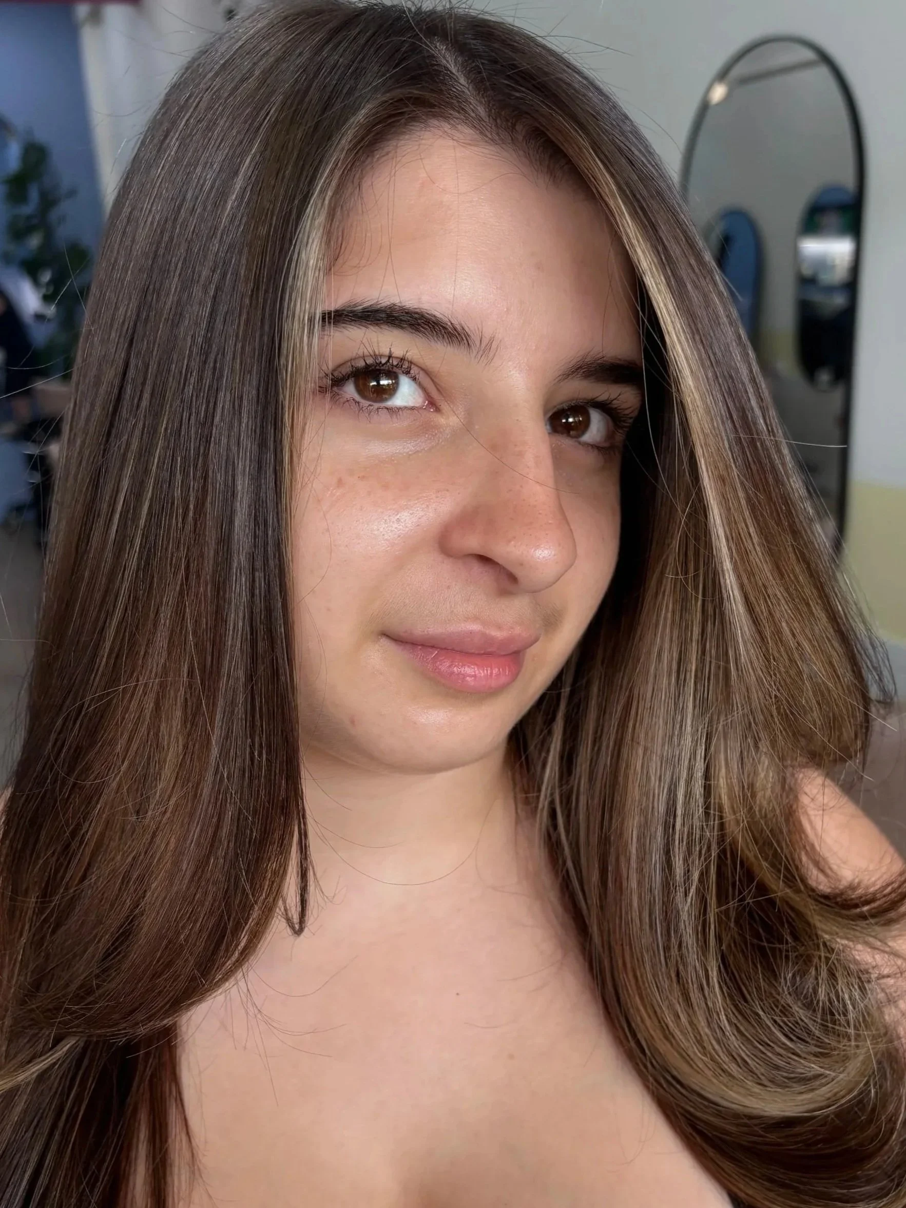 Close-up of a person with long, straight naturally coloured hair, slightly highlighted, wearing a black top