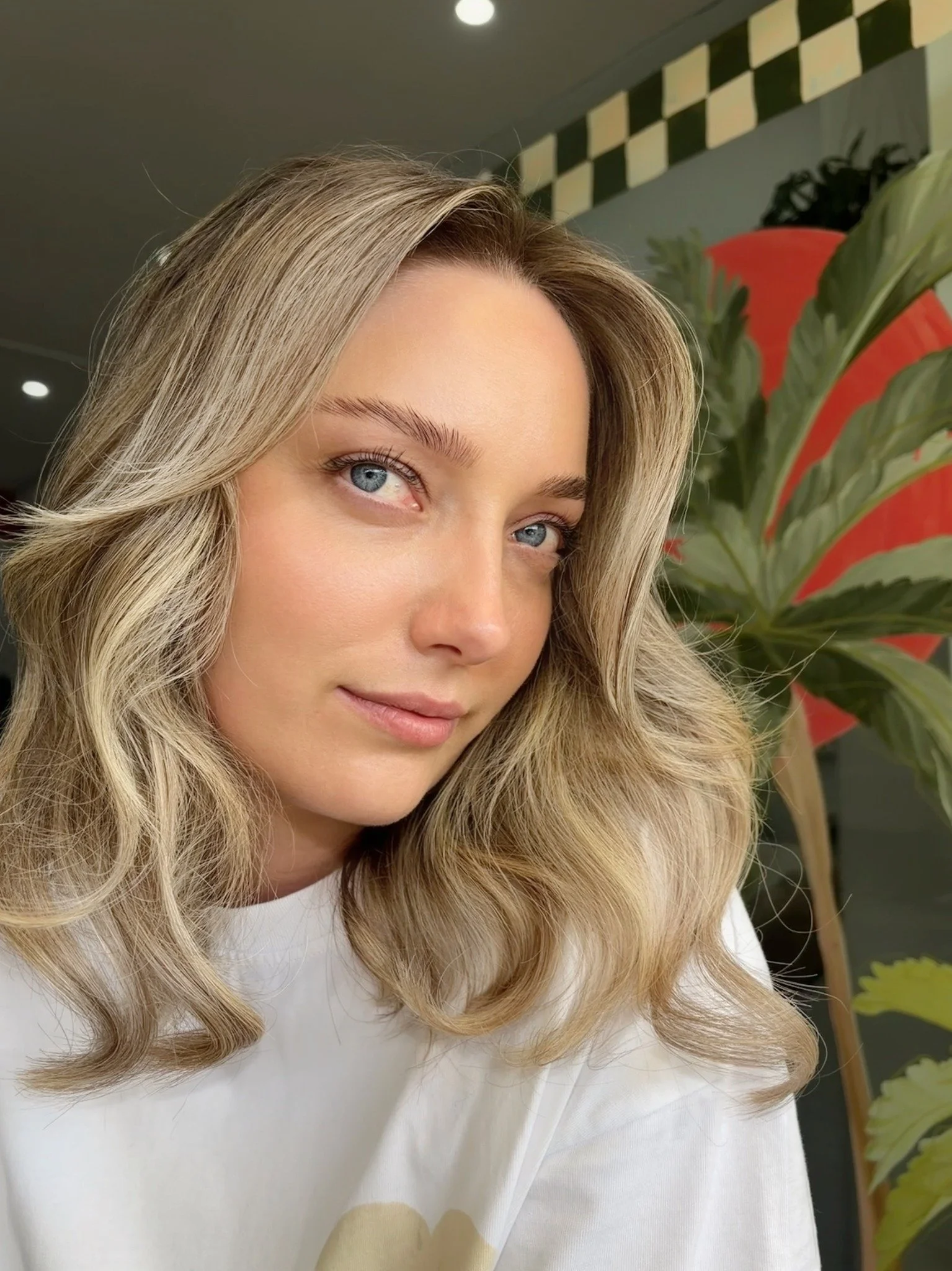 Blonde hair extensions blended into shoulder-length hair and styled in soft waves at Bhãva Salon.