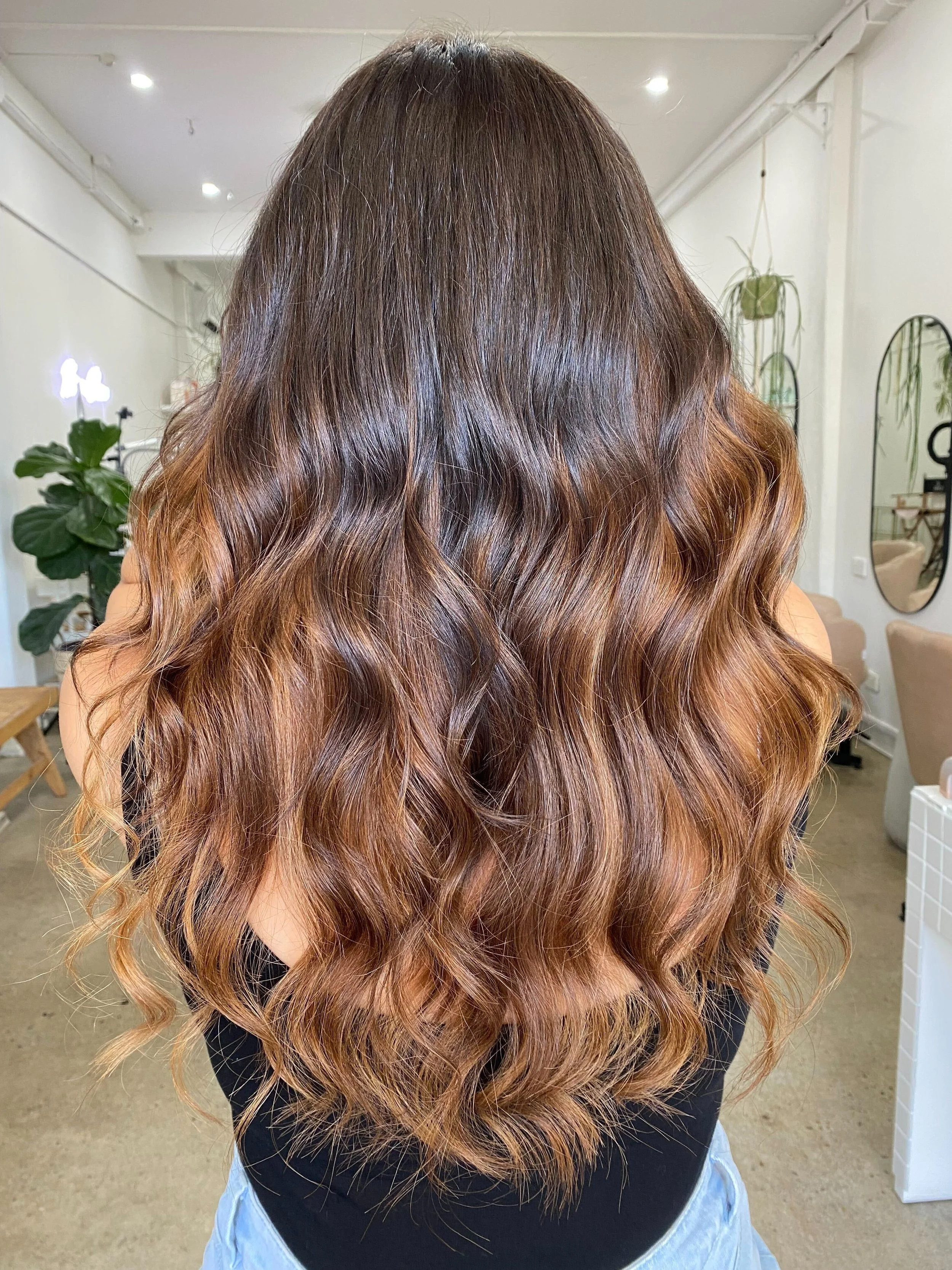 Woman with long wavy balayage hair in a salon setting.