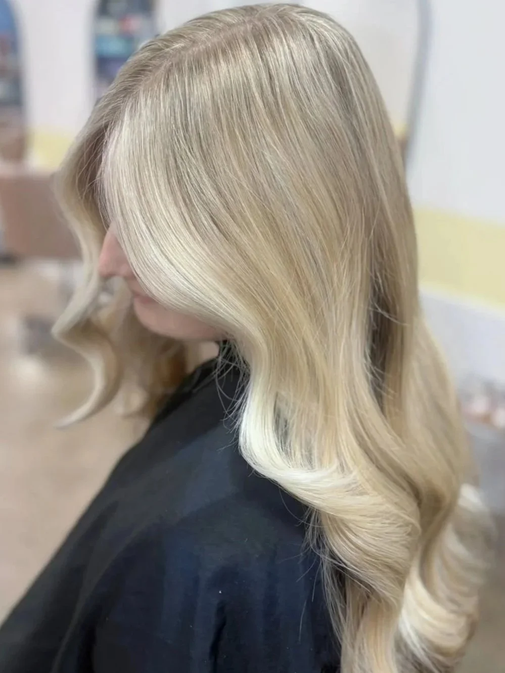 Woman with layered brown hair, looking down, in a salon setting.