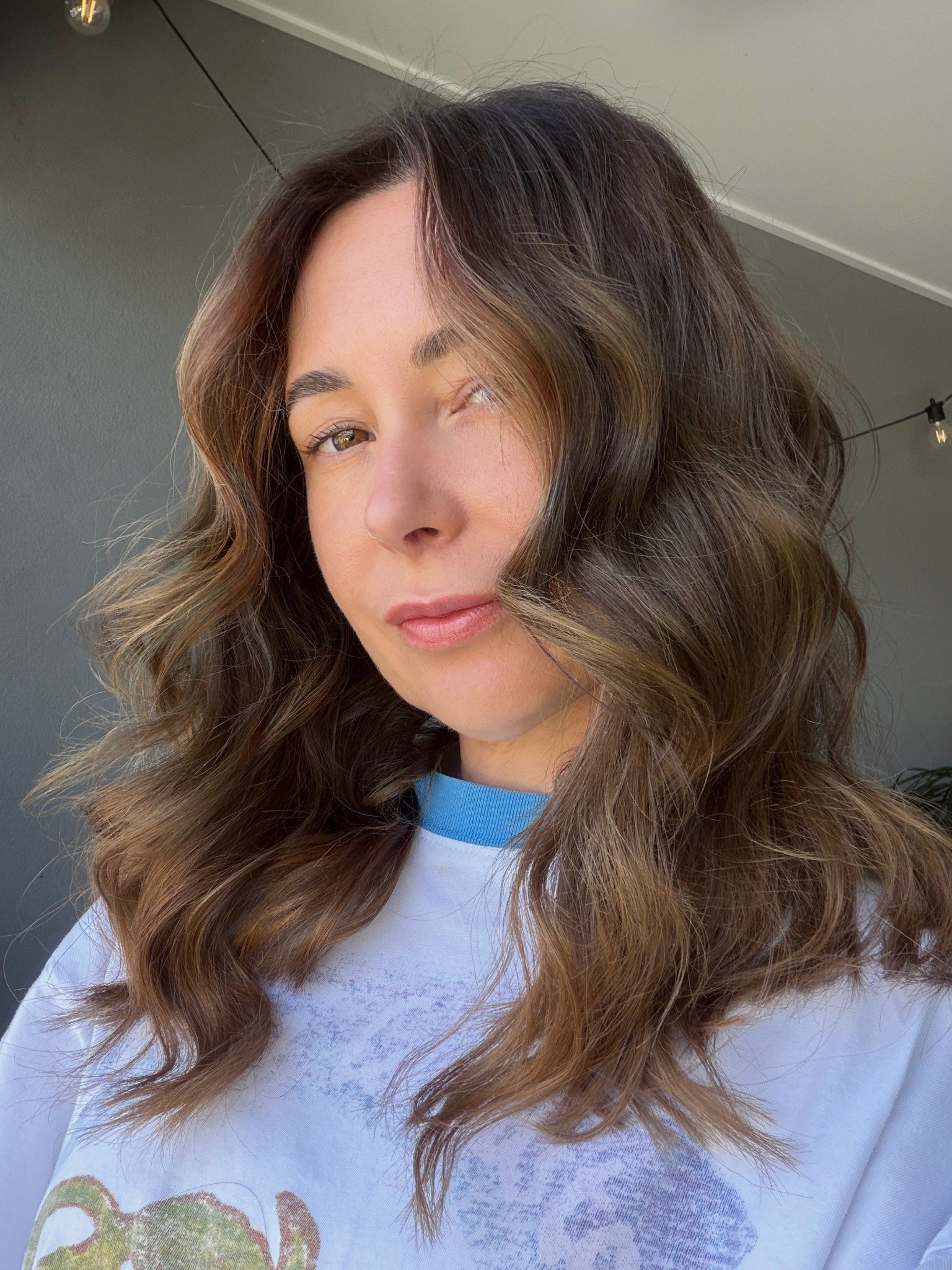 Shoulder-length brunette hair extensions with caramel highlights and soft waves at Bhãva Salon.